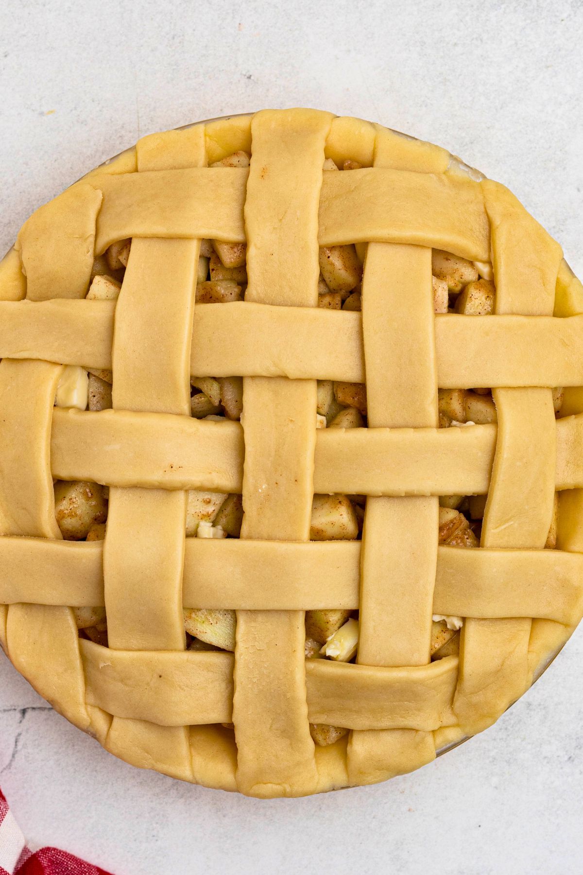 Unbaked apple pie with criss cross lattice crust on top. 