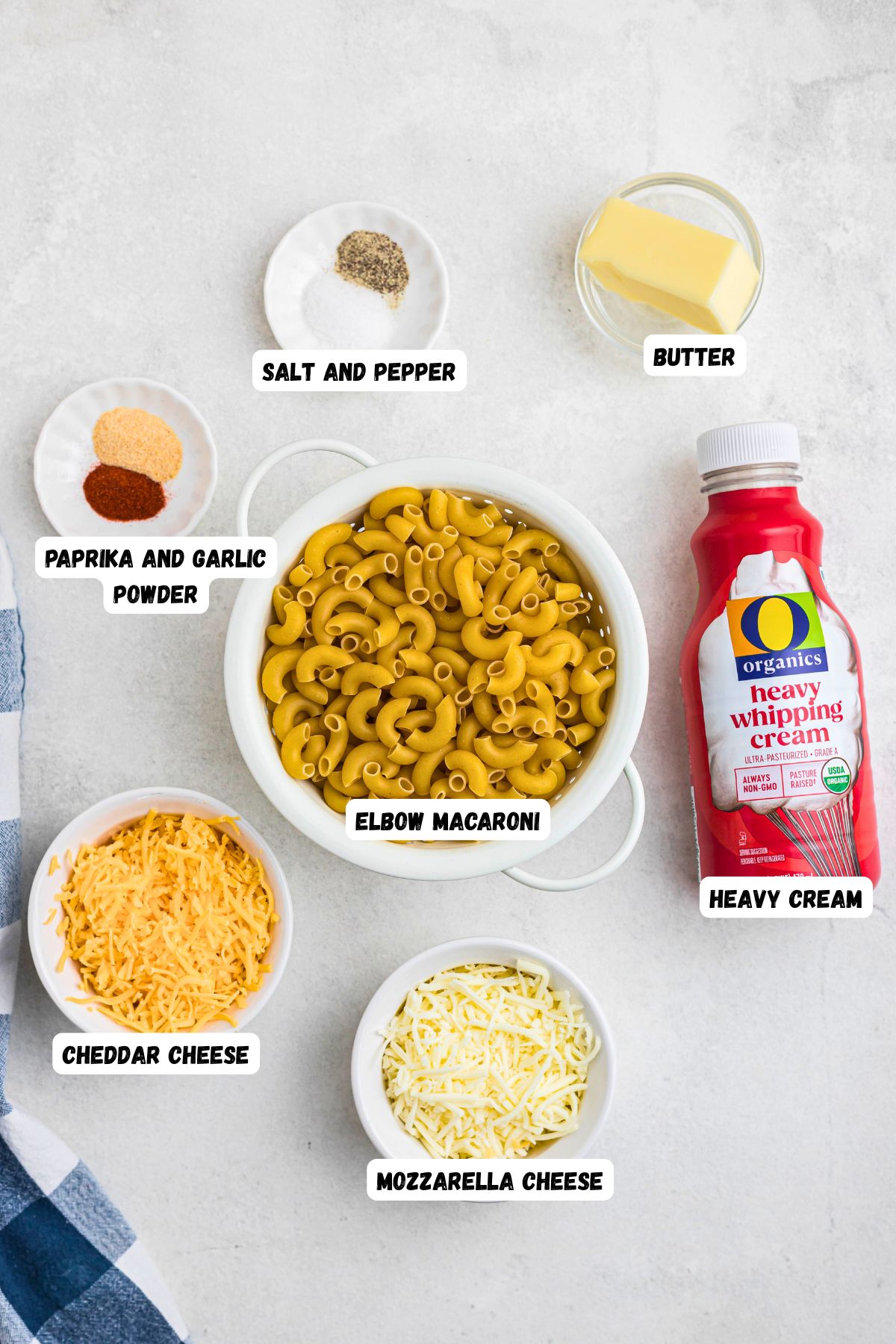 Ingredients needed to make baked mac and cheese in small white bowls on a marble table top.