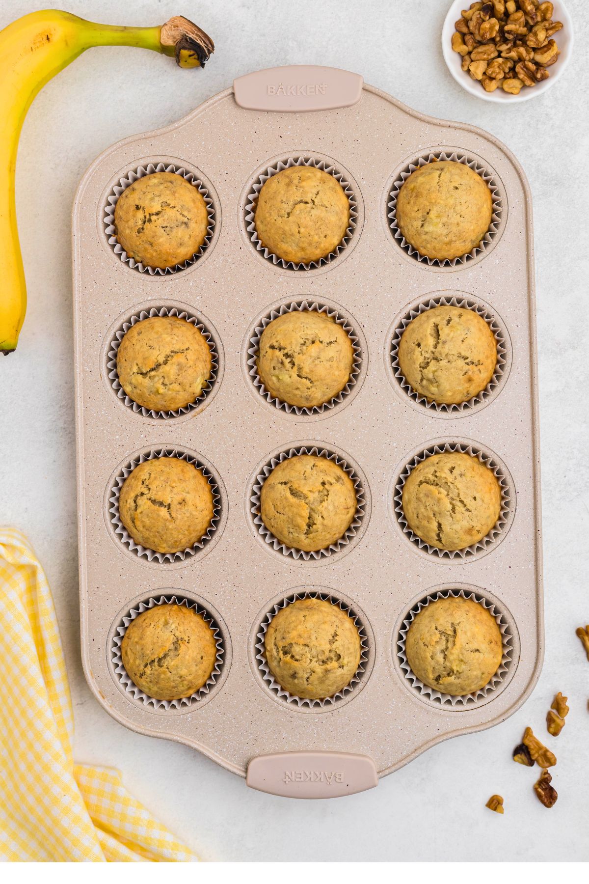 Baked muffins in a muffin pan on a marble table.