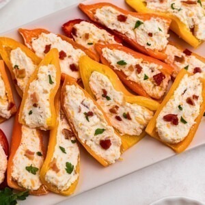 Stuffed cream cheese peppers on a rectangle white plate.