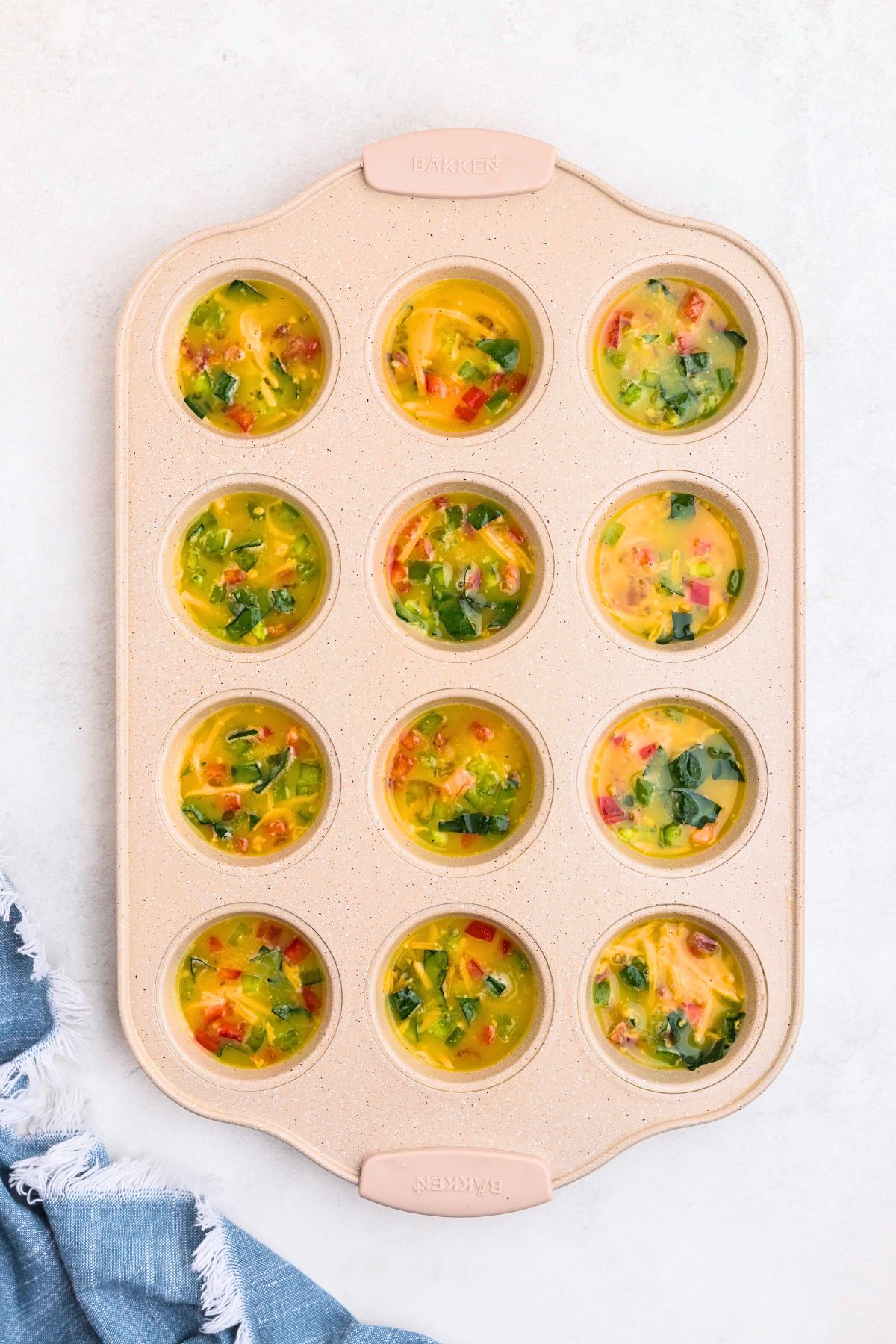 Egg mixture divided into muffin pan before baking. 