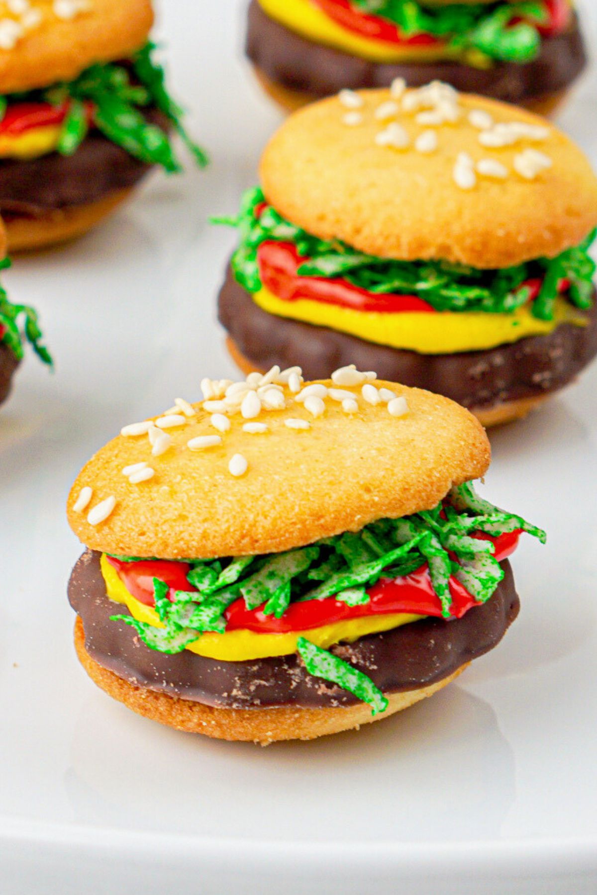 Wafer cookies with frosting, shredded coconut, and icing in between so they look like a hamburger.
