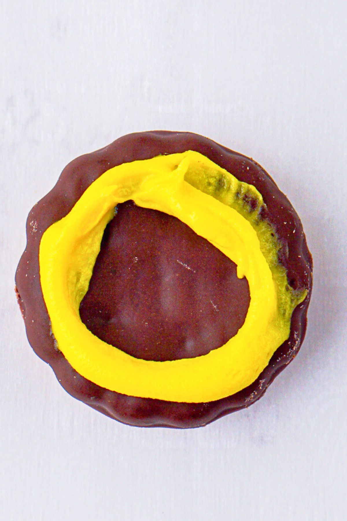 Chocolate cookie topped with yellow icing. 