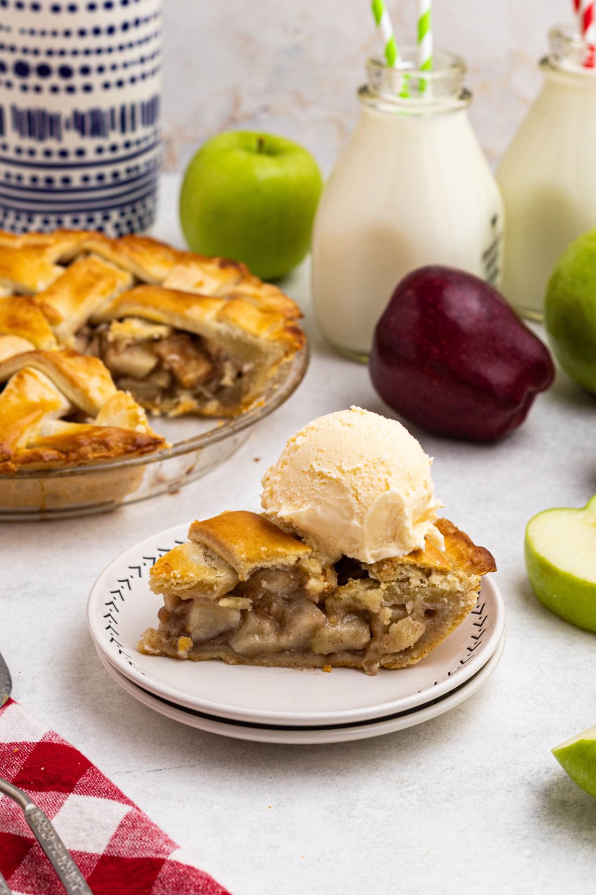 A slice of pie on small white plate with a scoop of vanilla ice cream on top. 