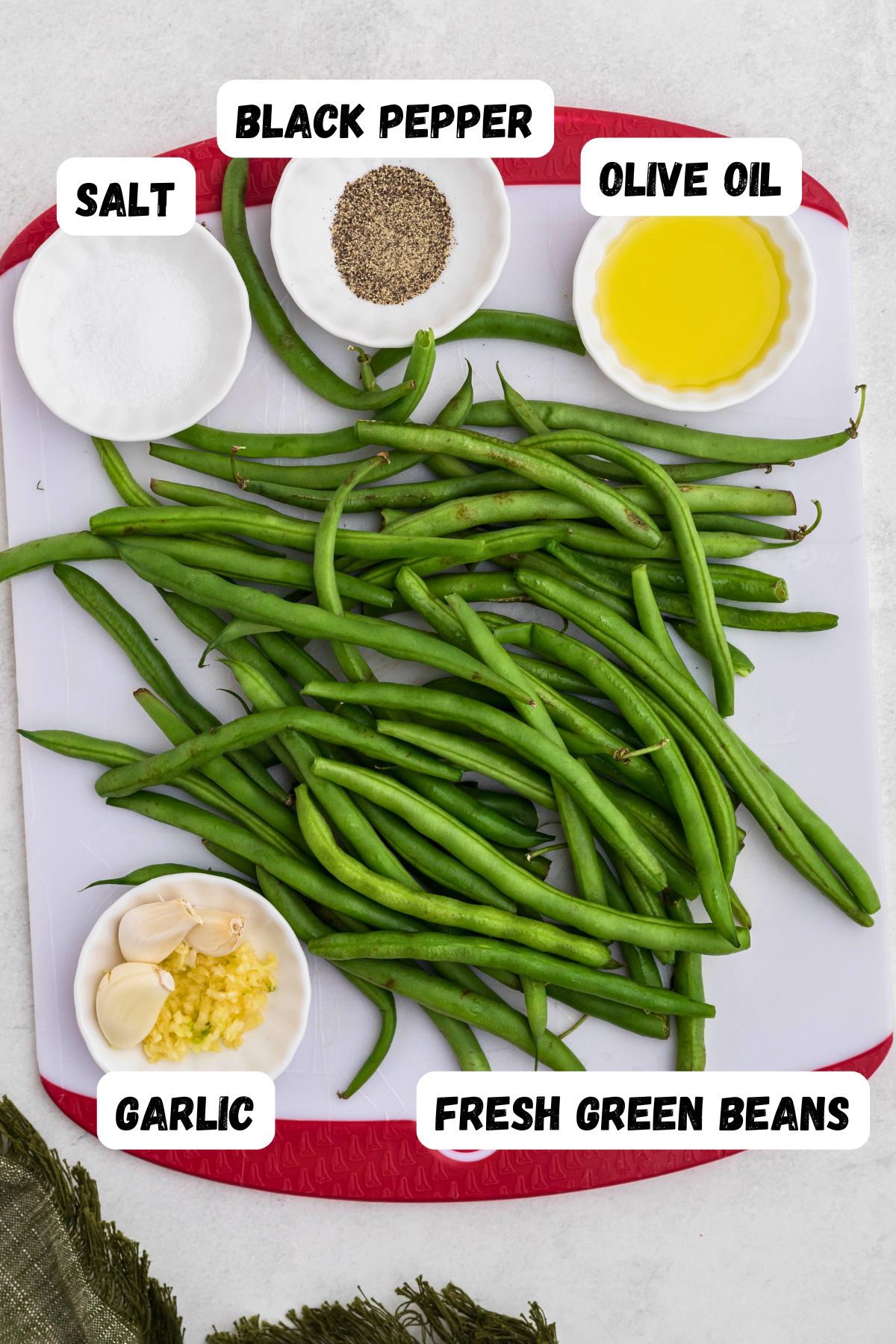 Ingredients like fresh green beans, and seasonings,  measured into small bowls on a marble table. 