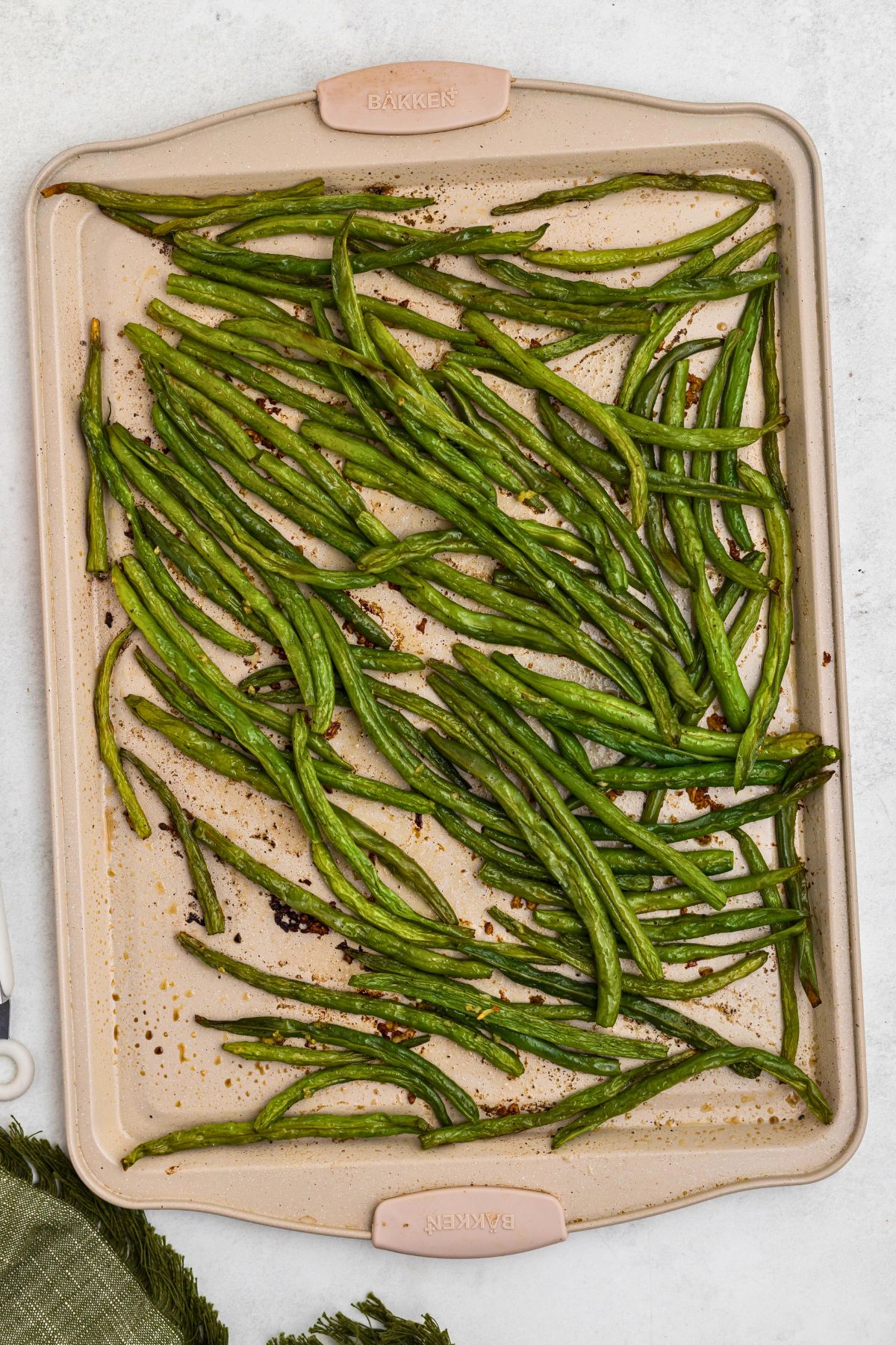 Roasted green beans on a baking sheet after being cooked in the oven. 