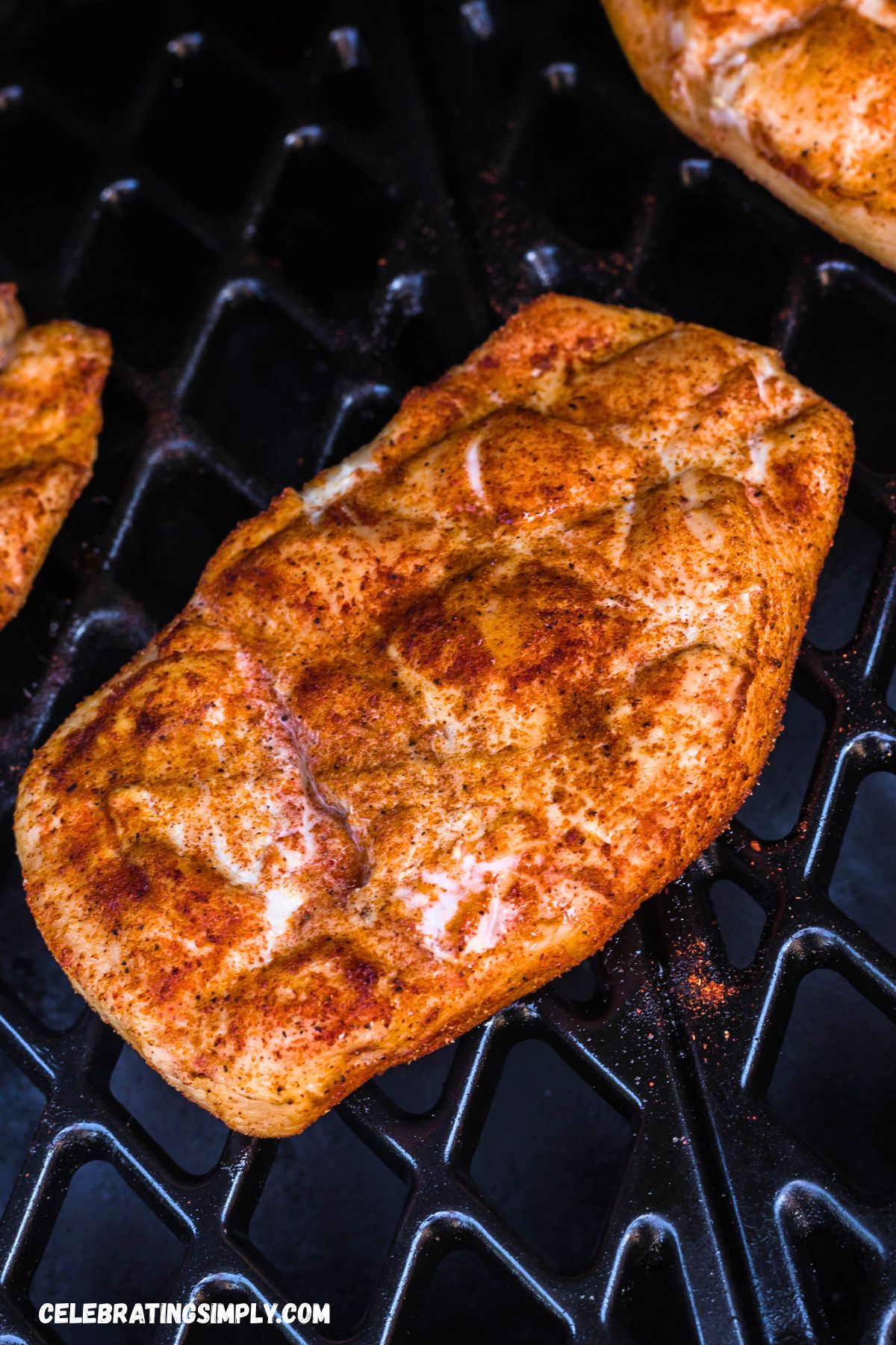 Seasoned chicken breast on a grill rack on a smoker. 