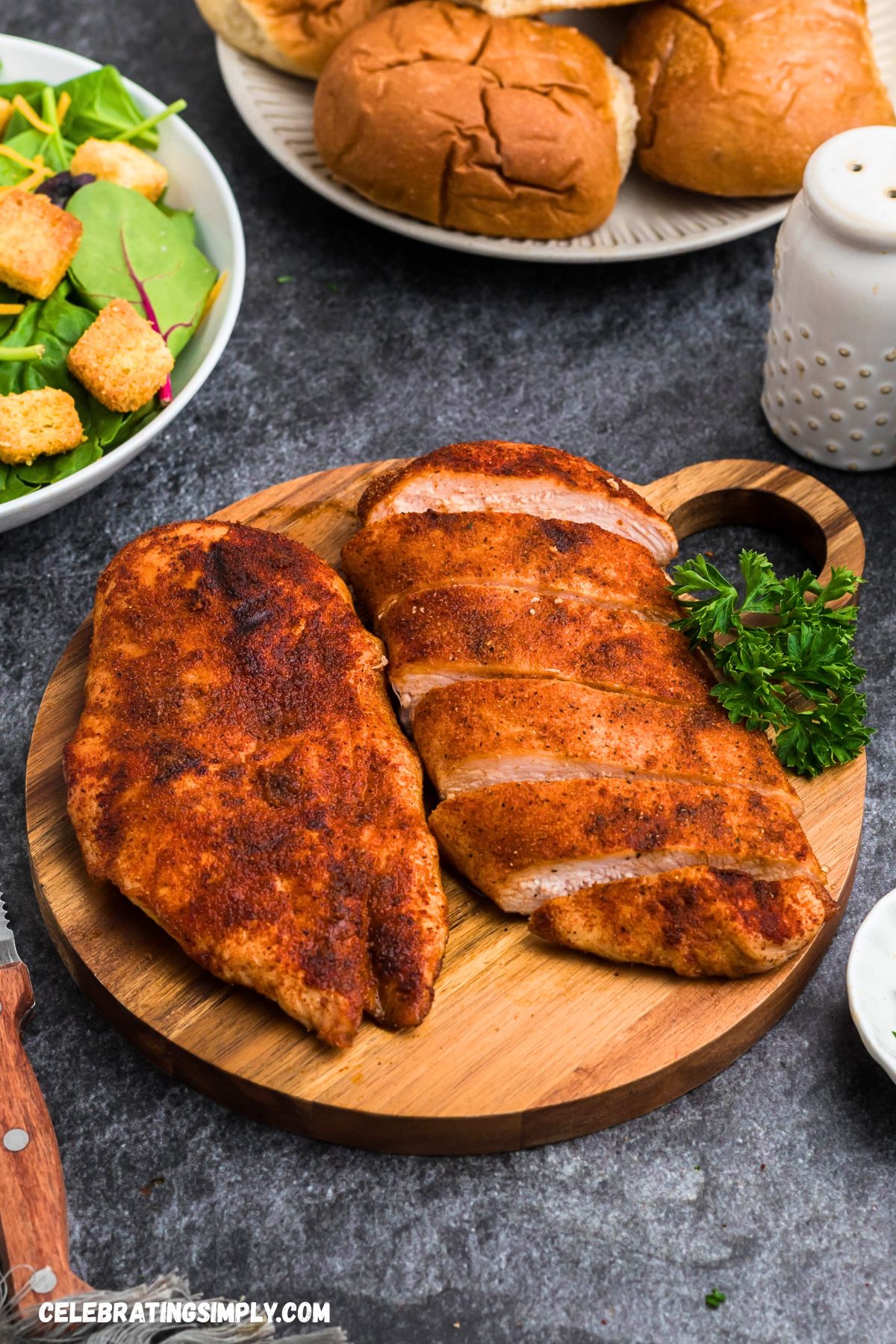 Seasoned smoked chicken resting a wooden cutting board. 