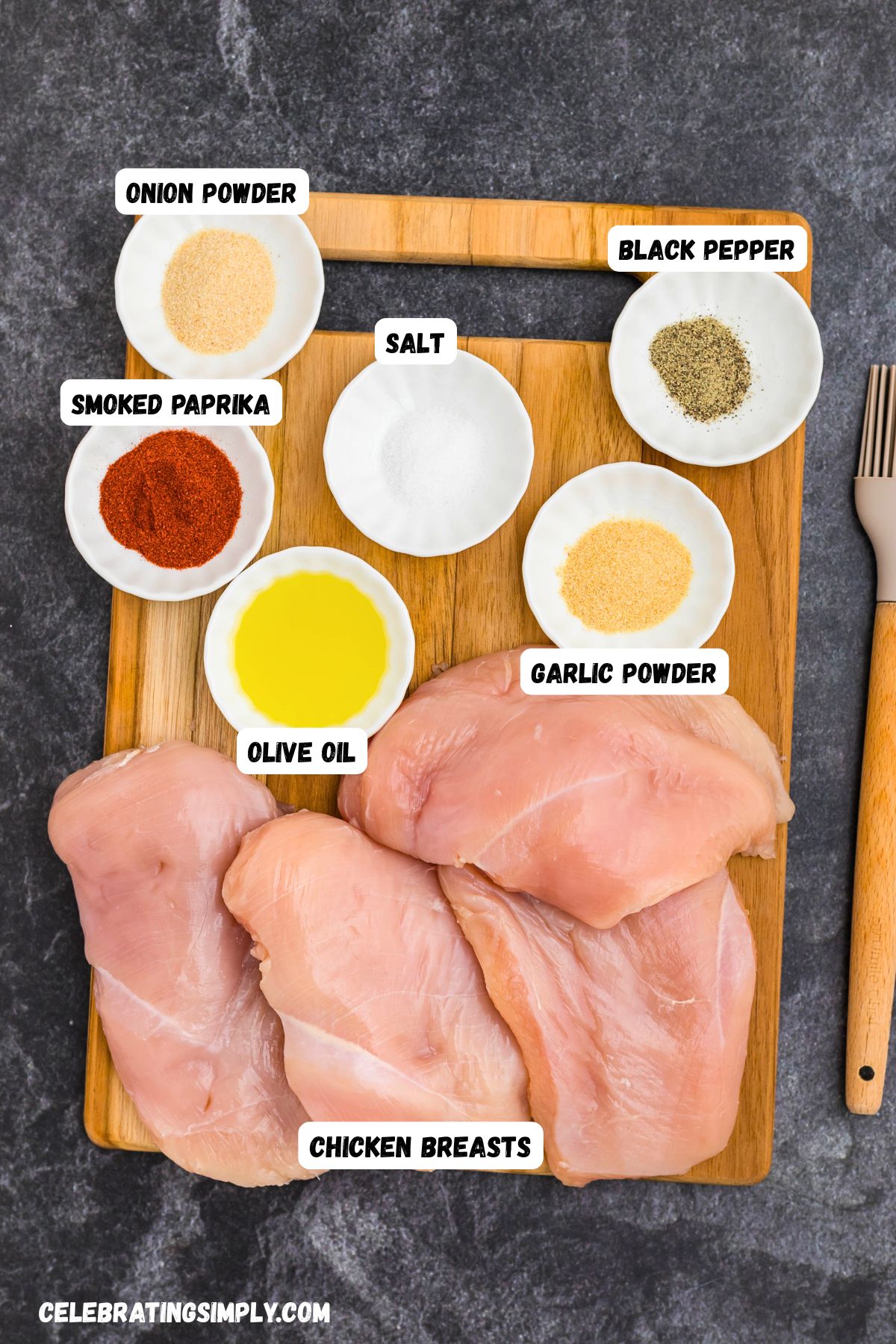 Ingredients measured into small white dishes on top of a cutting board with uncooked chicken breasts on the side. 