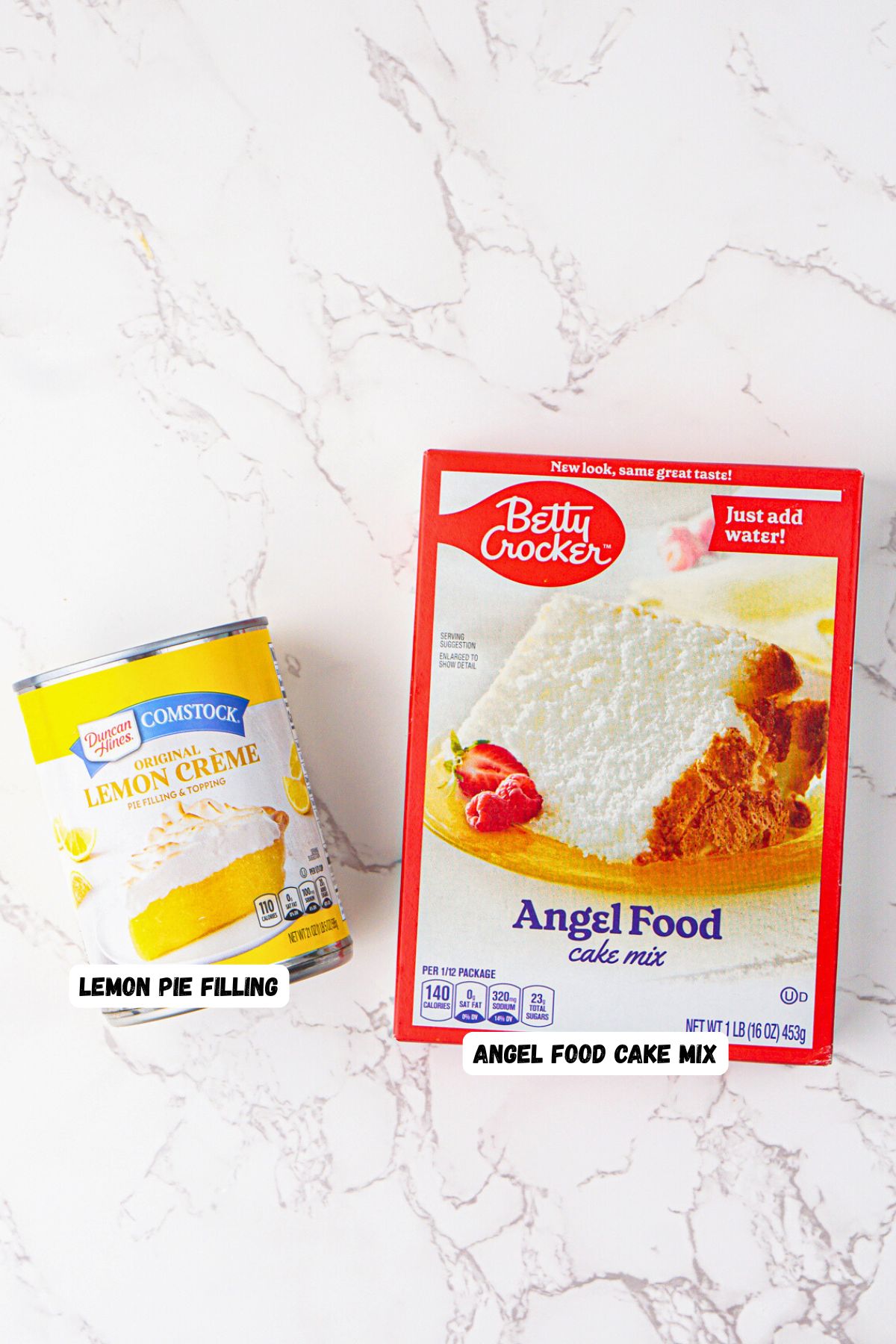 Box of angel food cake mix and can of lemon pie filling on a white marble table. 