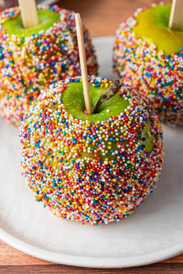 Green apples dipped in a coating and rolled in colorful sprinkles.