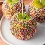 Green apples dipped in a coating and rolled in colorful sprinkles.