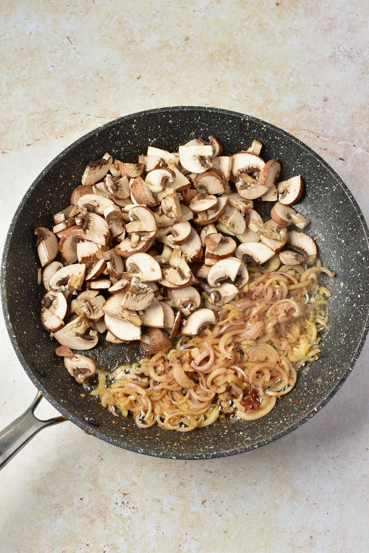 Mushrooms and other ingredients being cooked in a large skillet. 
