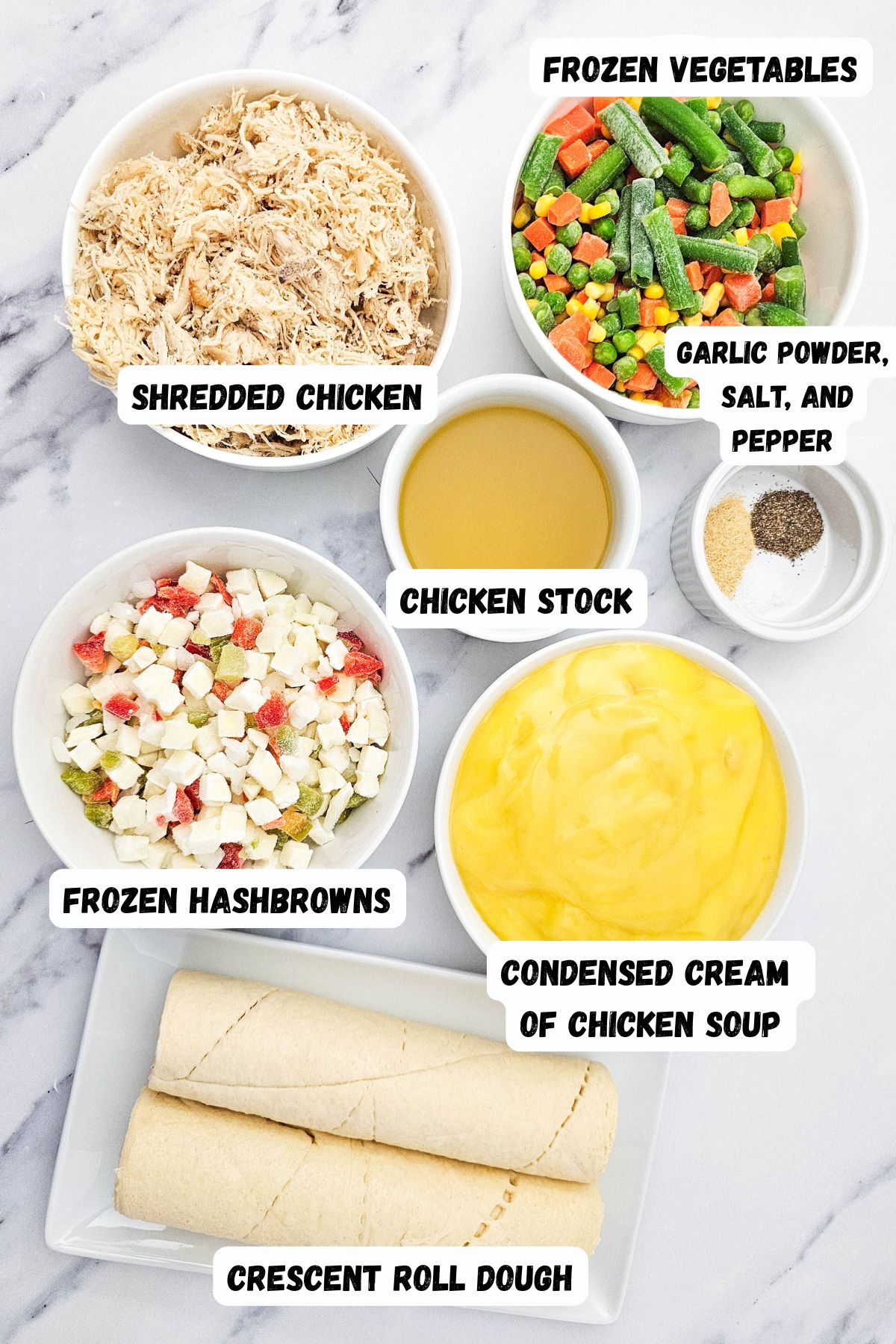 Ingredients needed to make chicken pot pie casserole measured in small white bowls, on a white marble table. 