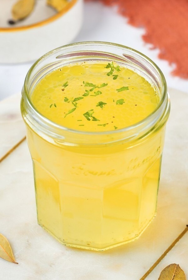 Small jar filled with yellow chicken stock.
