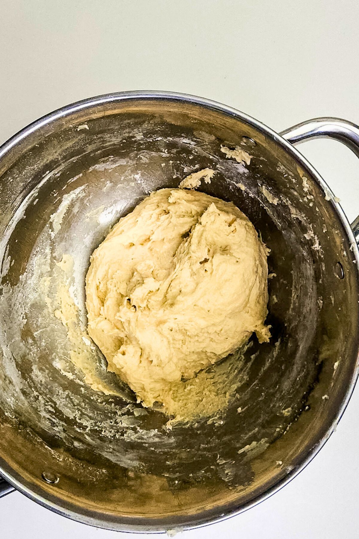 Soft dough mixed together in a large silver bowl.