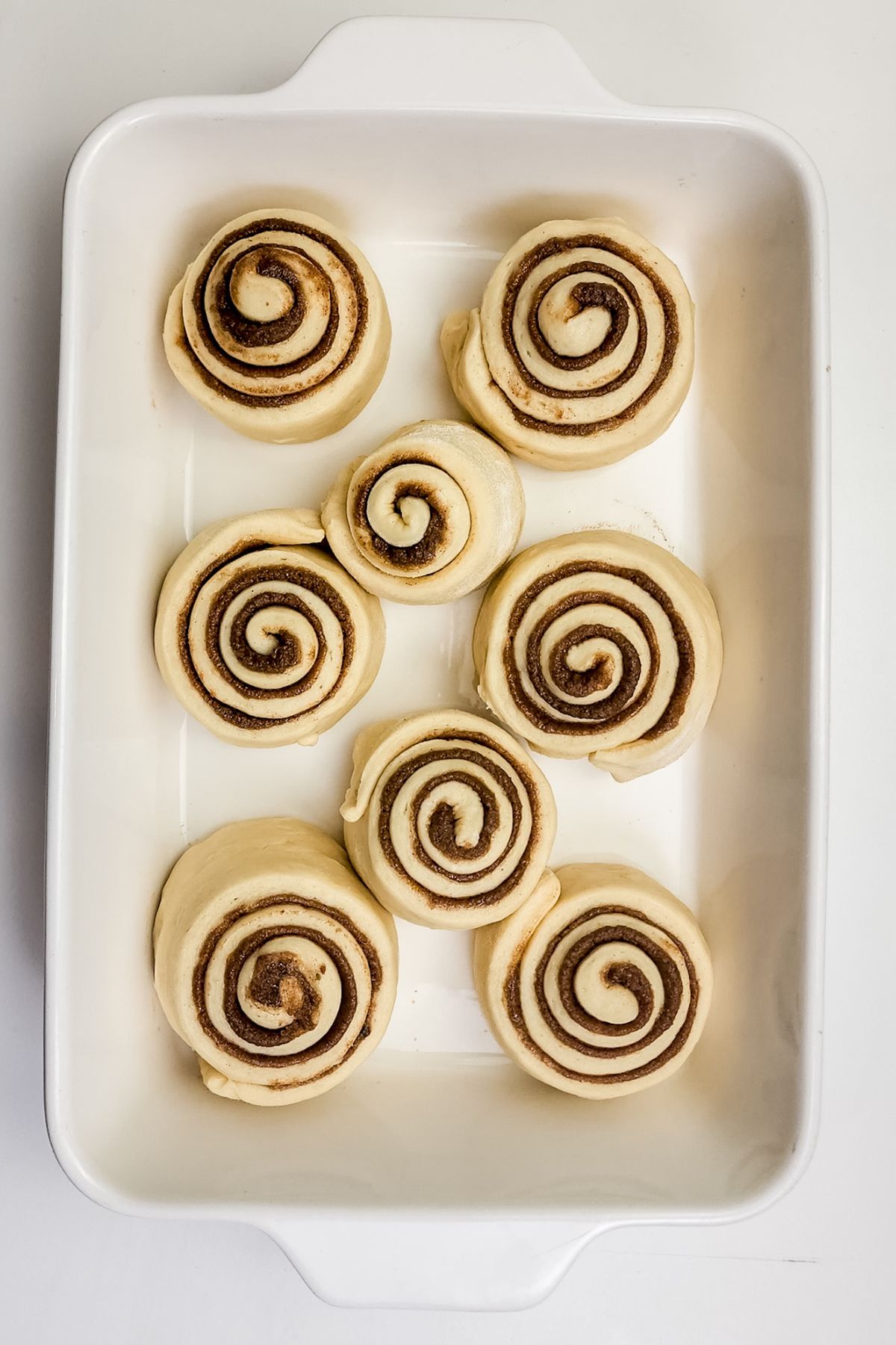 Uncooked rolls in a white pan before baking.