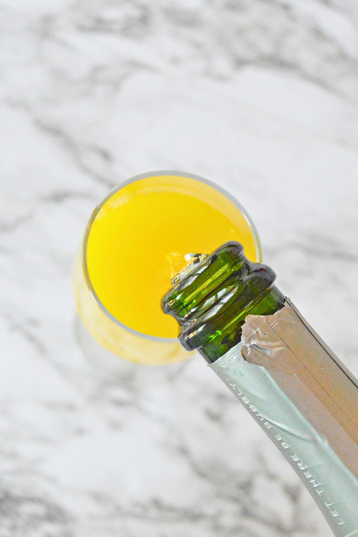 Champagne poured into glass on a marble table. 
