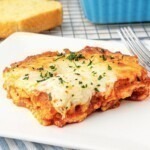 Cheese slice of ravioli lasagna on a square white plate.