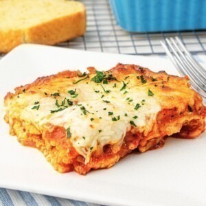 Cheese slice of ravioli lasagna on a square white plate.