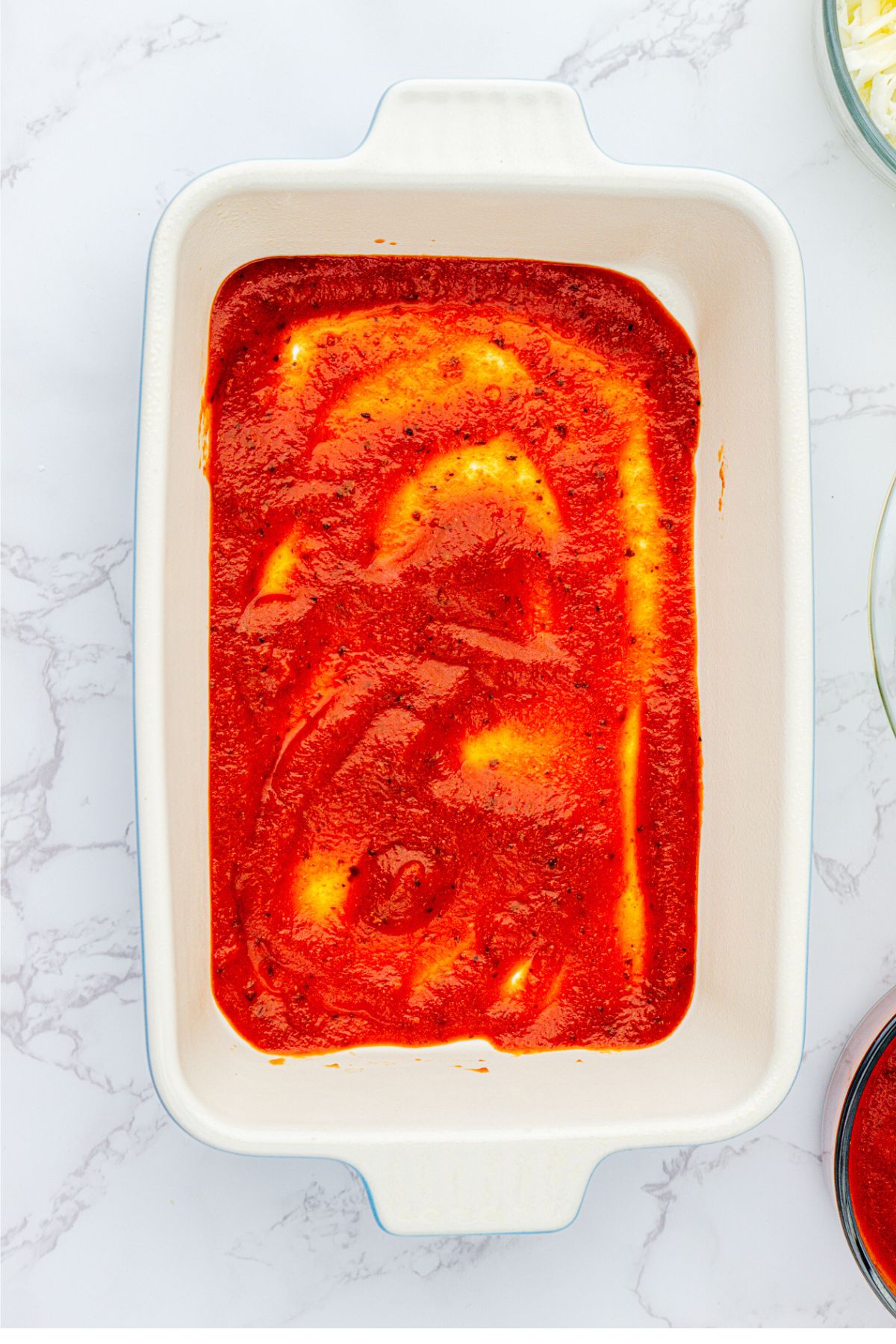 White rectangle casserole dish with red sauce. 