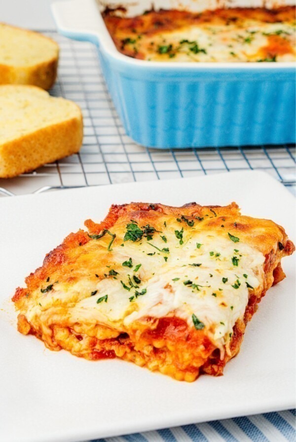 Cheese slice of ravioli lasagna on a square white plate.