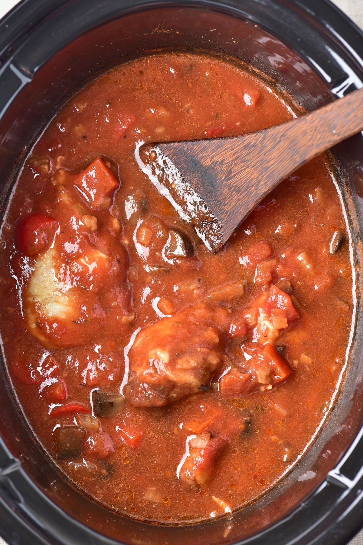Cooked chicken in the slow cooker in a red sauce after cooking for hours. 