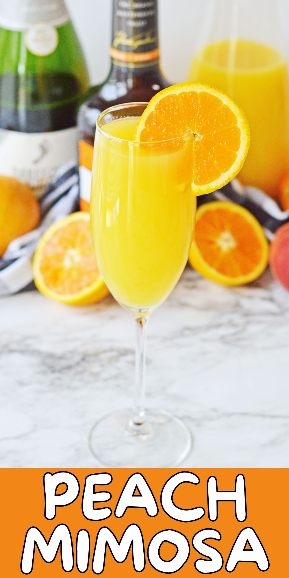 Peach mimosa with an orange slice for garnish on a white marble table.