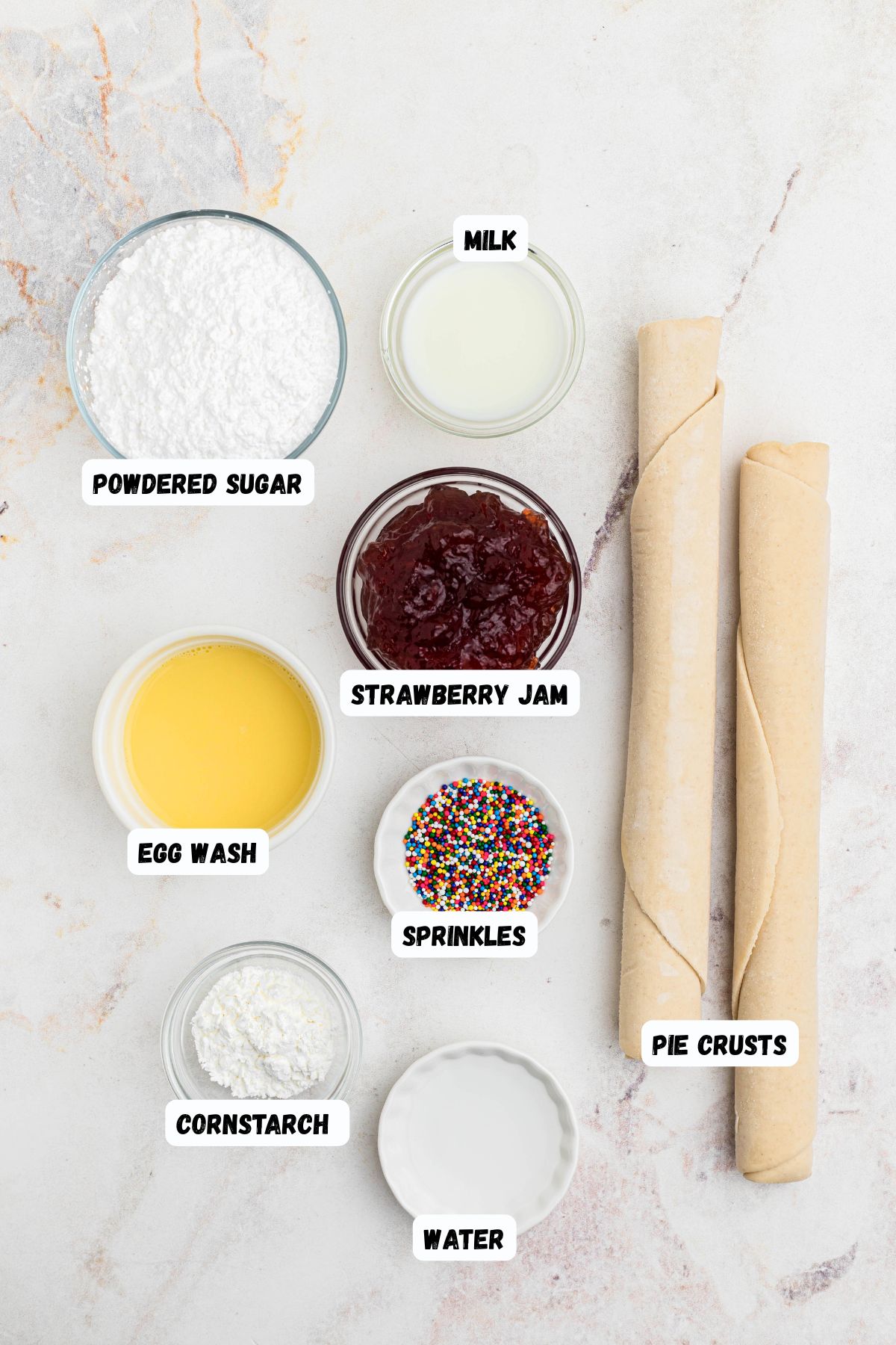 Ingredients needed to make homemade pop tarts on a marble table, and labeled. 