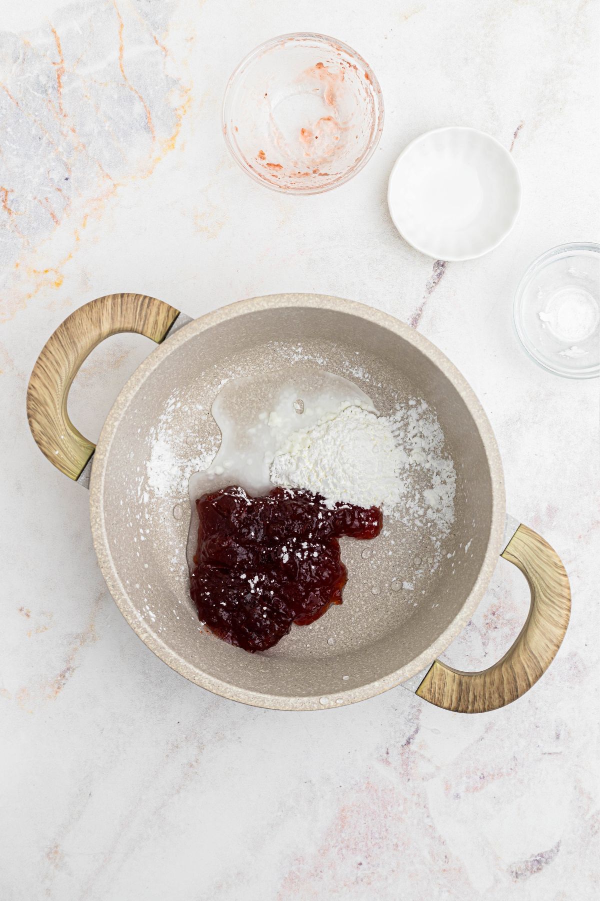 Cornstarch, water, and jam, being mixed together in a saucepan. 
