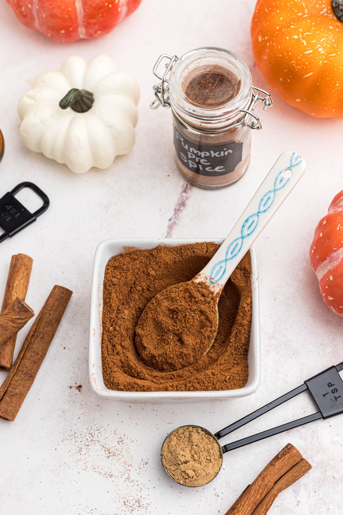 Spices mixed together in a small square dish with a white spoon in the center.