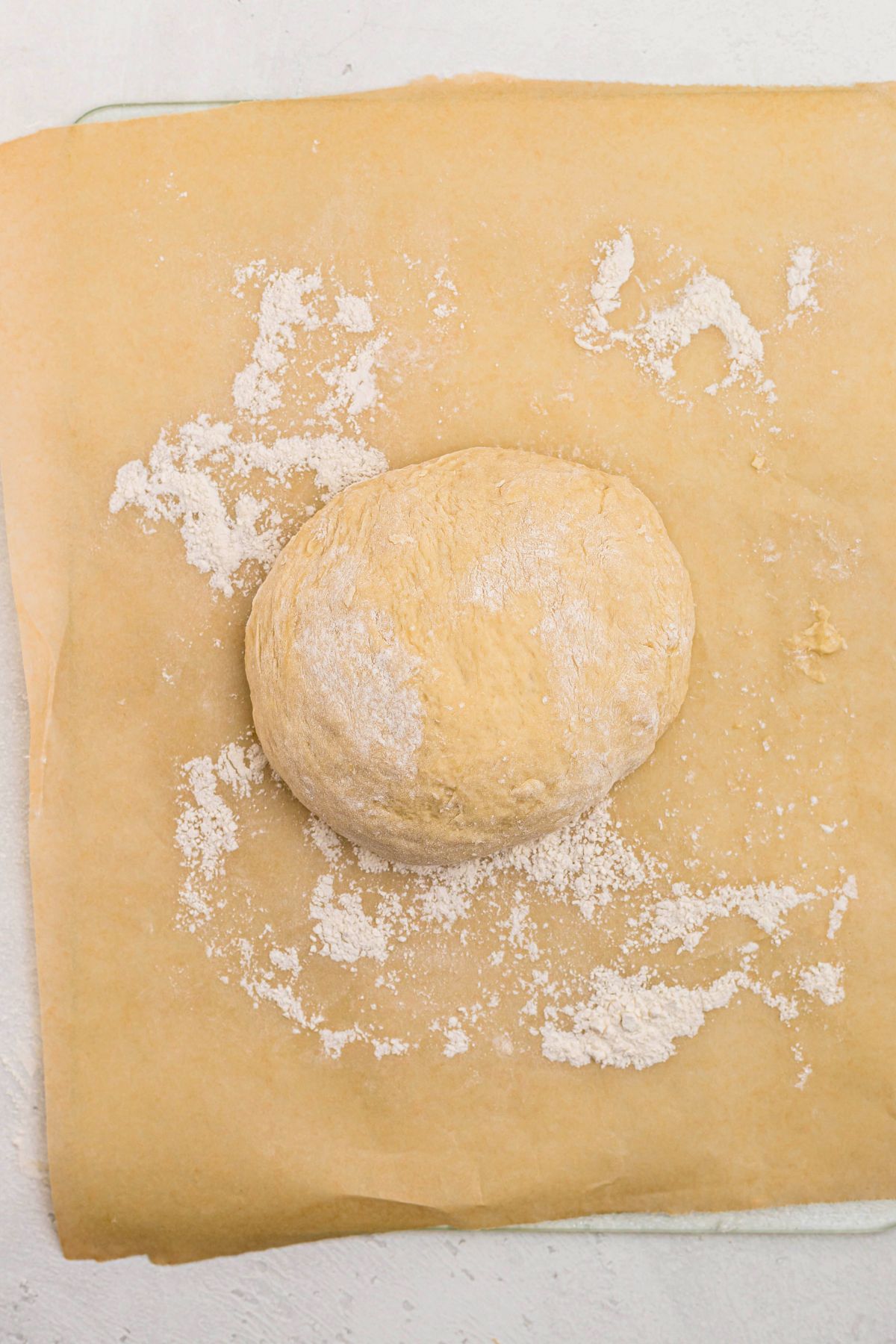 On a lightly floured surface, bread dough kneaded and shaped into a ball before letting it rise to double. 