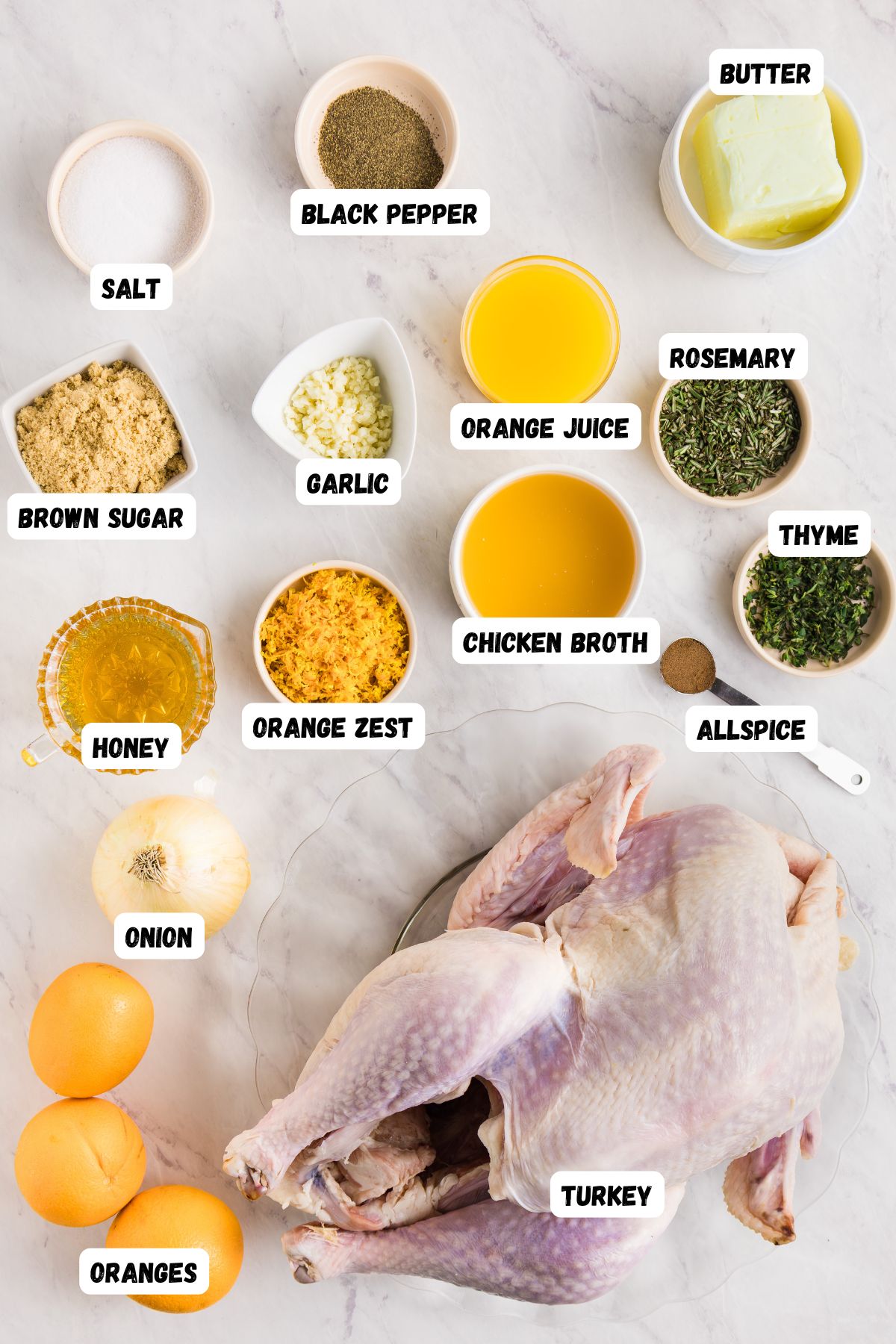 Ingredients to make roasted turkey measured into small bowls and labeled, on a white marble table, along with an uncooked turkey. 