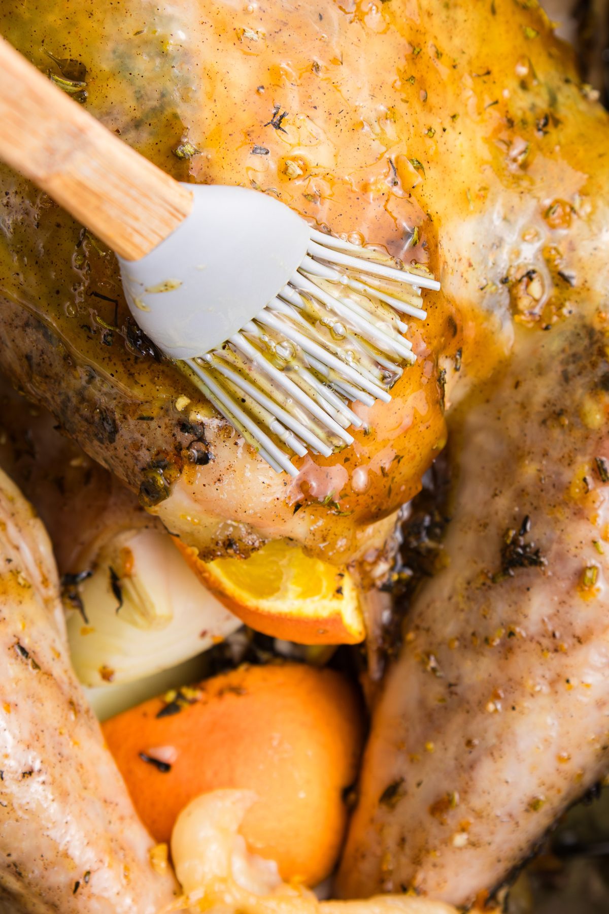 Orange glaze being brushed on a turkey during cooking. 