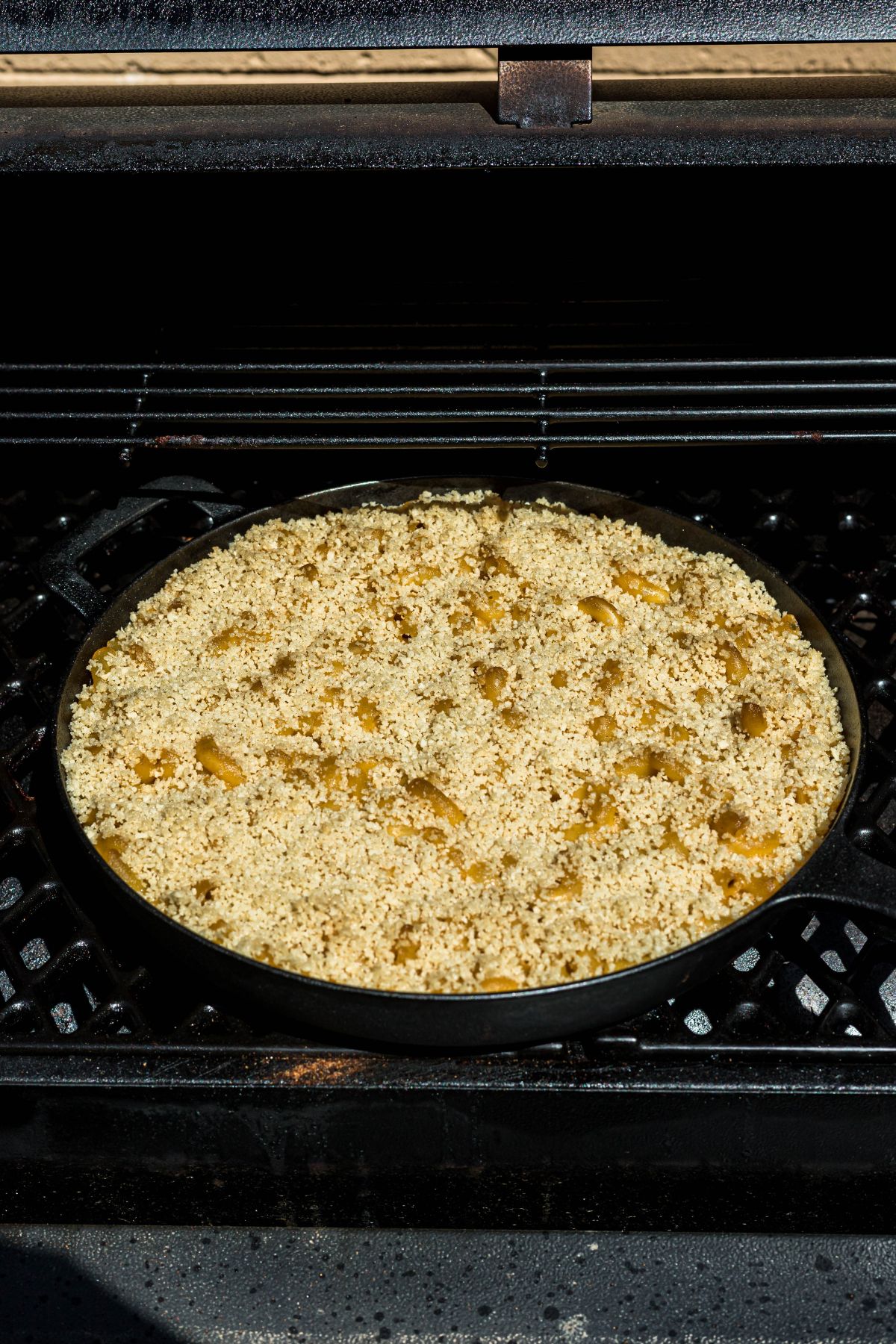 Cast iron skillet with mac and cheese, in a smoker grill. 