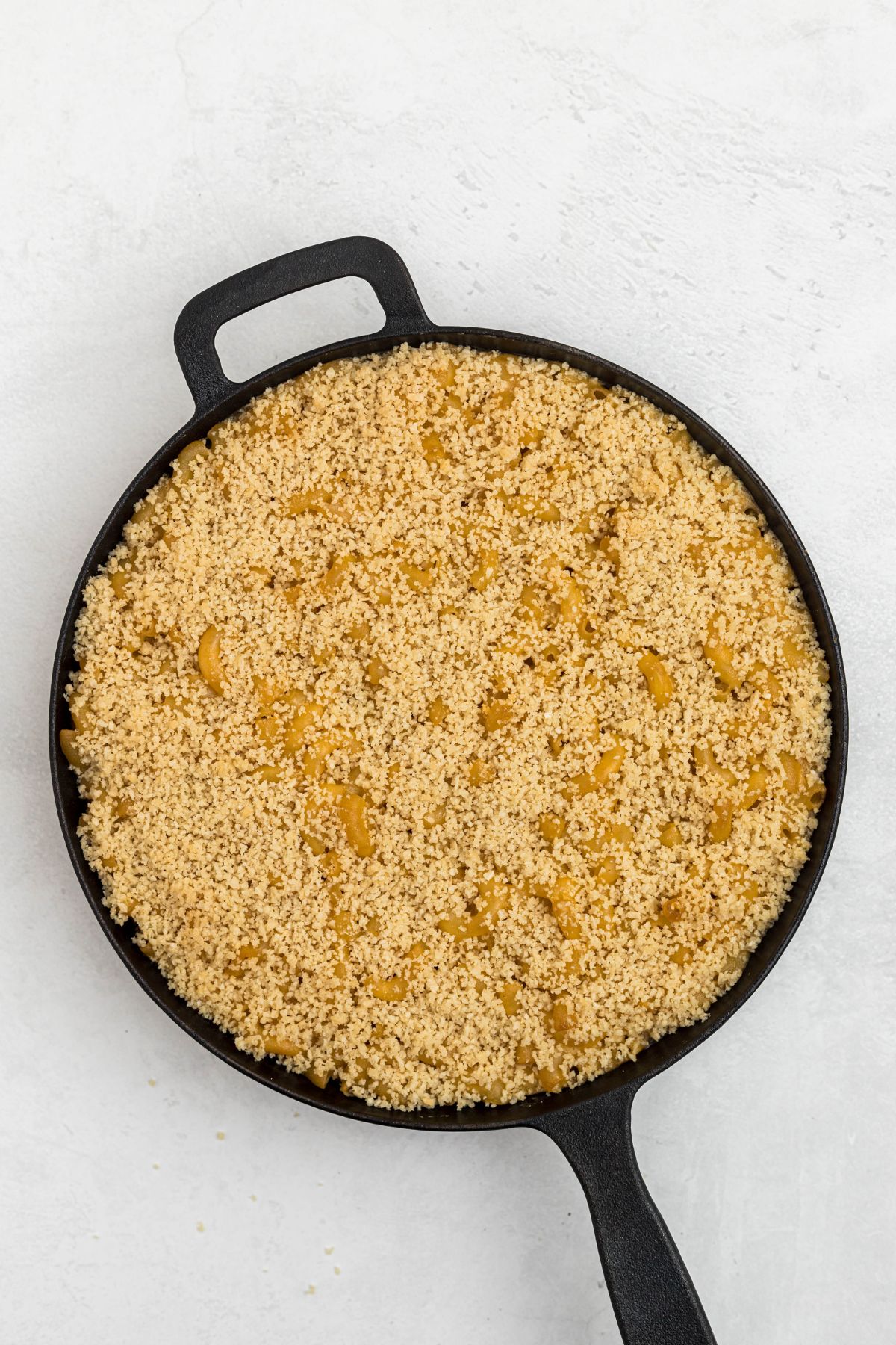 Cast iron skillet with mac and cheese, topped with bread crumbs, after smoking, but before putting in the oven on broil. 