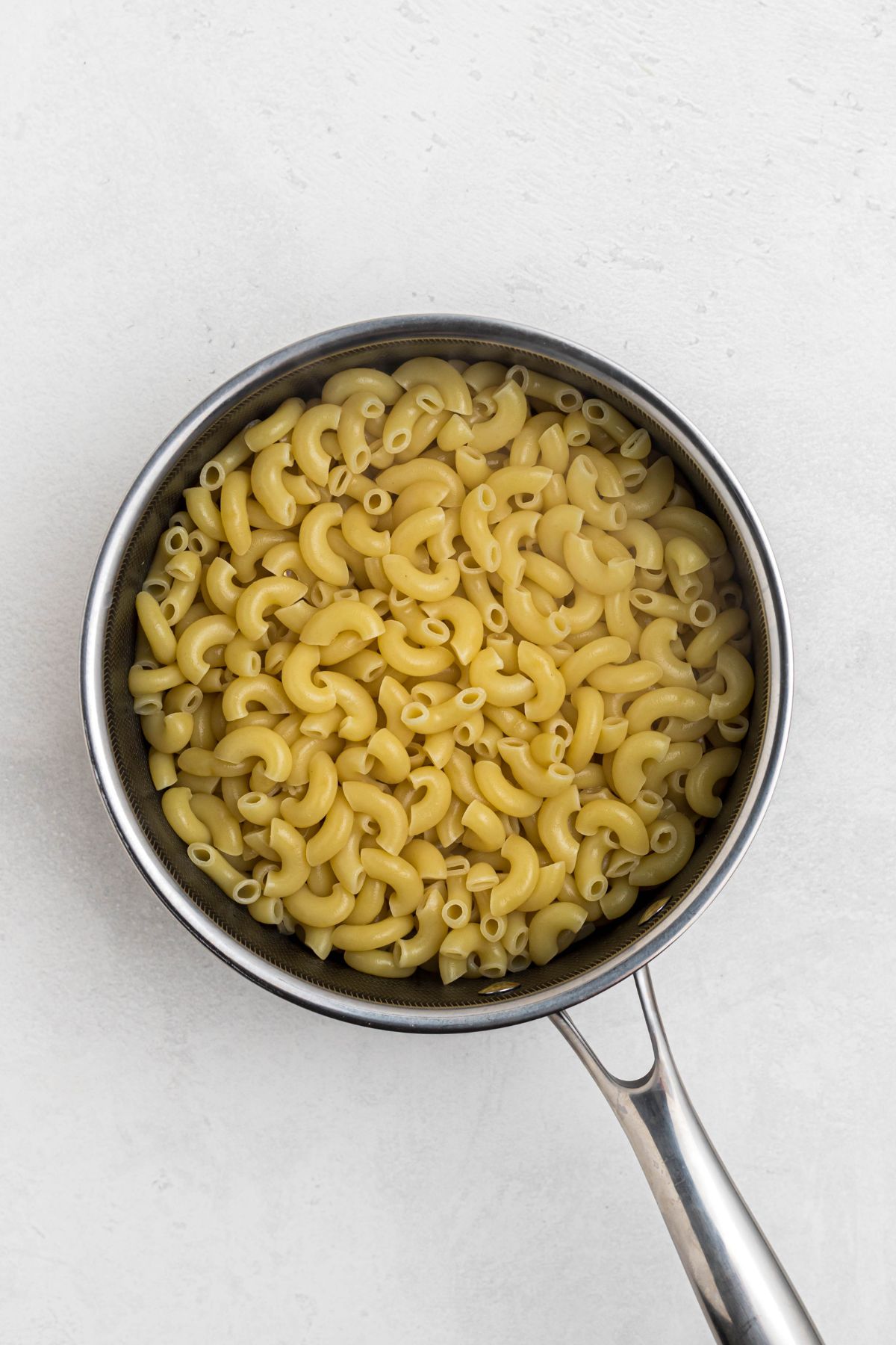 Macaroni lightly cooked in a saucepan. 