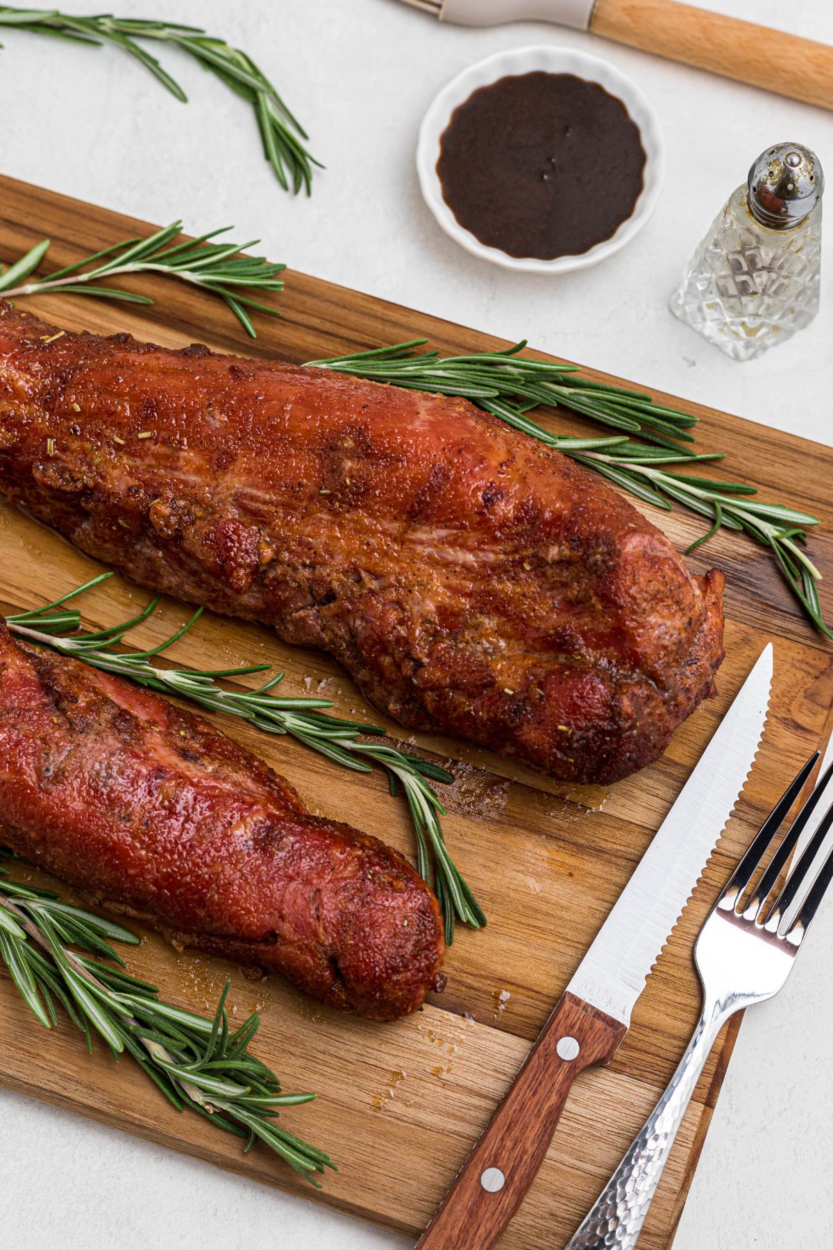 Smoked tenderloins on a wooden cutting board, after having glaze cooked on top and before cutting. 