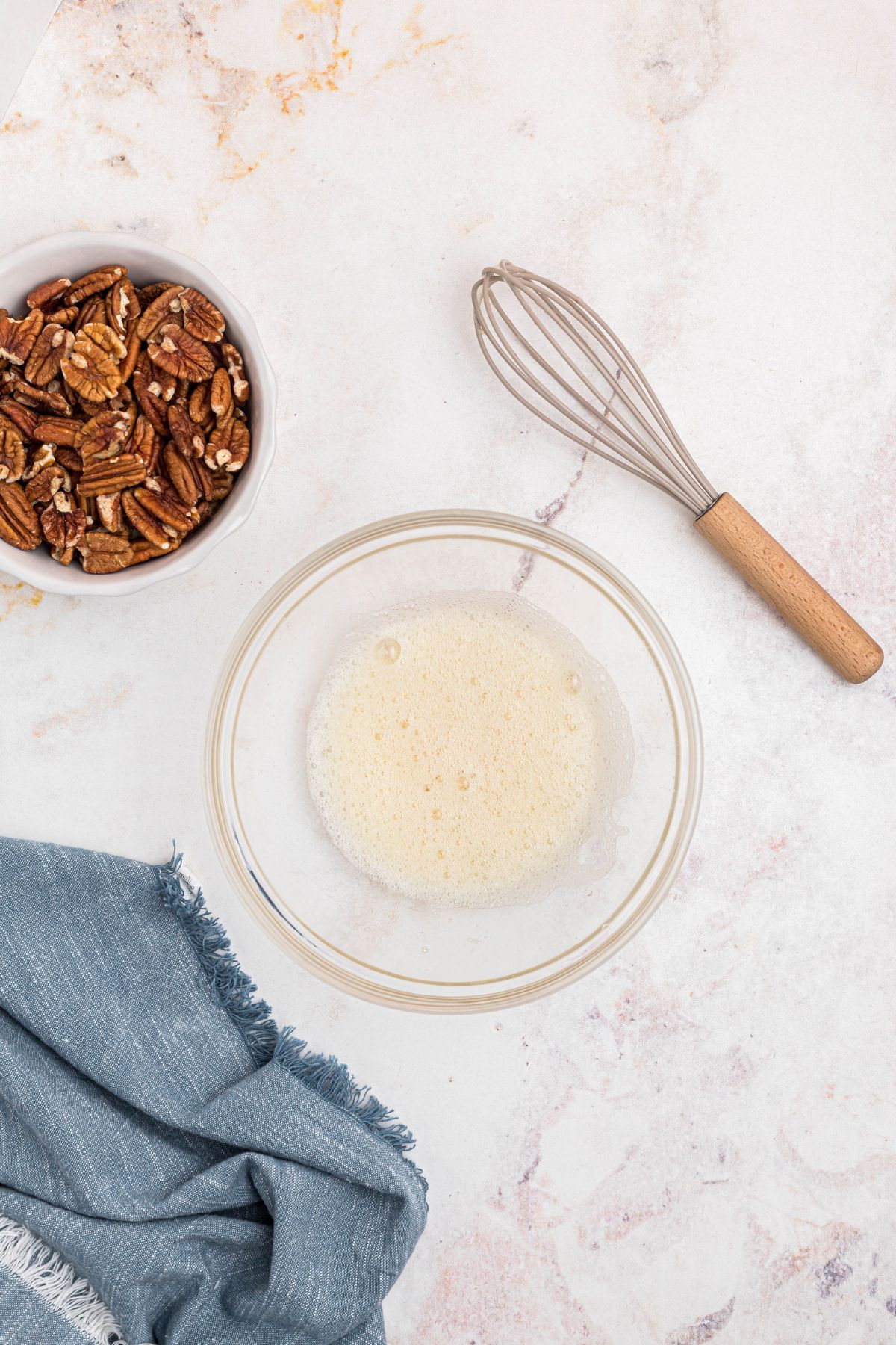 Egg white whisked with water in a clear glass bowl. 