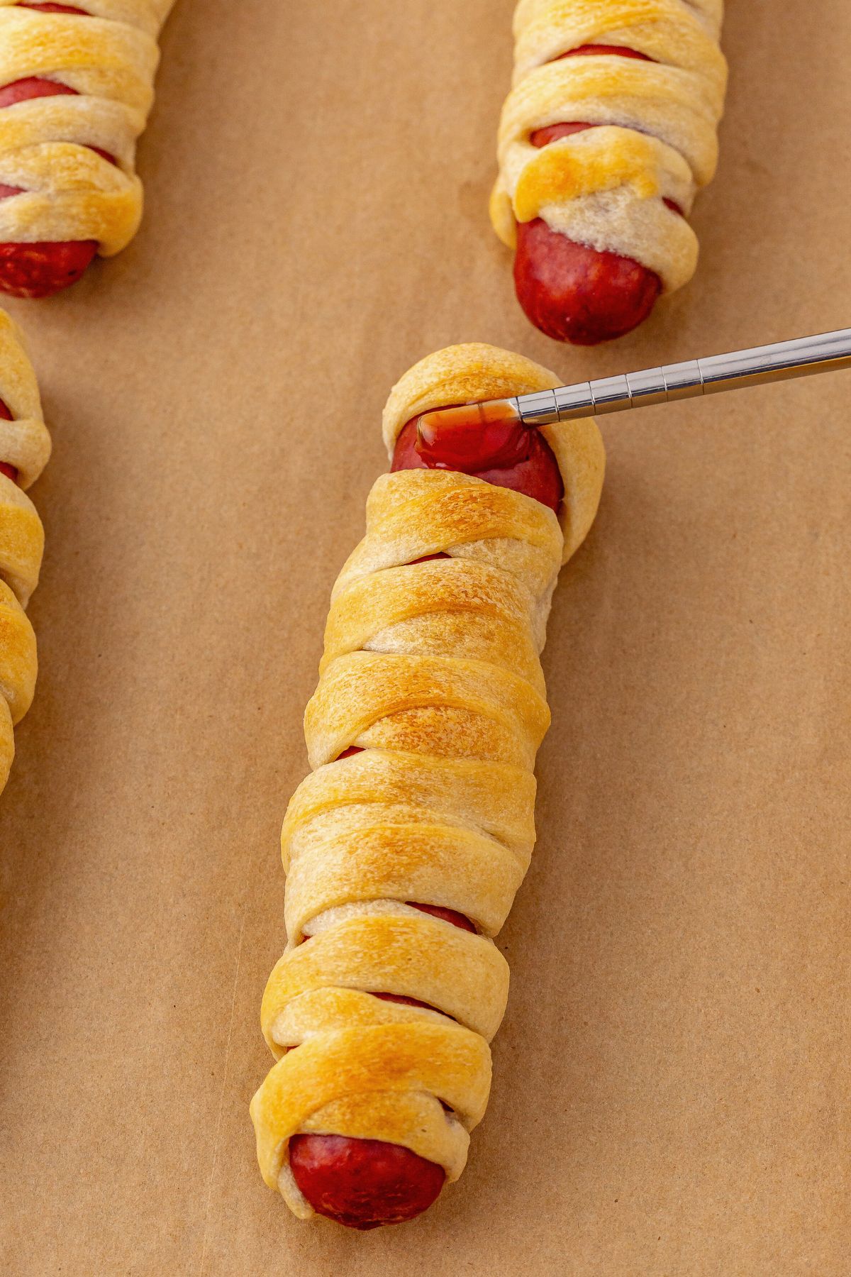 Ketchup being added to mummy dog to use to hold candy eyes in place.