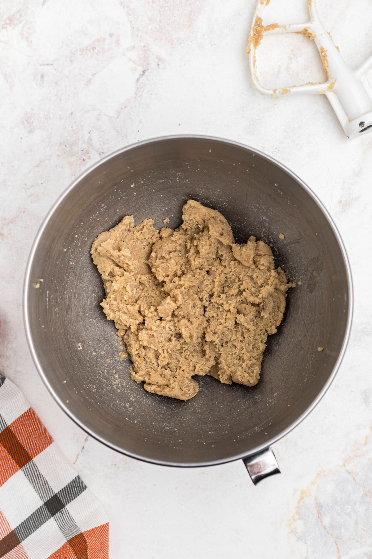 Butter and sugars being mixed together to form soft dough.