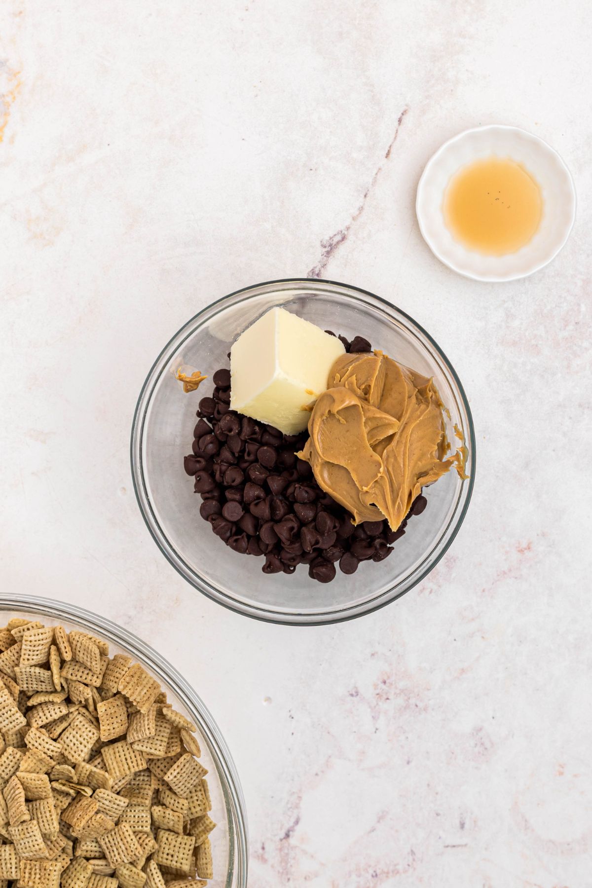 Peanut butter, chocolate, and other ingredients, in a clear microwave safe glass bowl before being melted and stirred together. 