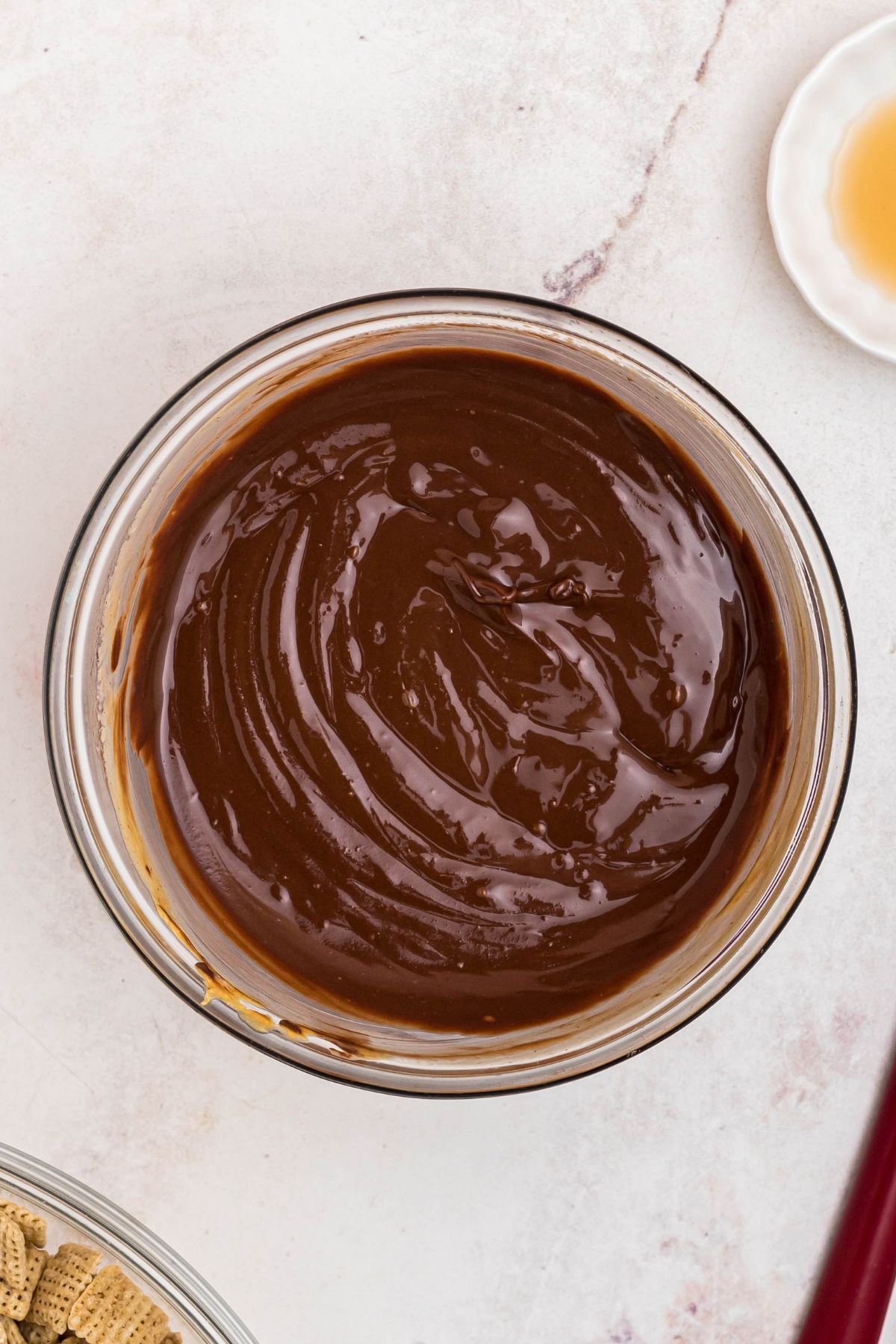 Melted chocolate and peanut butter, and butter, mixed together in a clear glass bowl. 