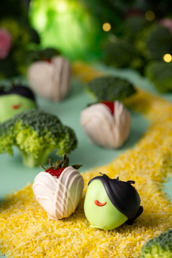 Wicked themed dipped strawberries on a green table with yellow rice for a road.