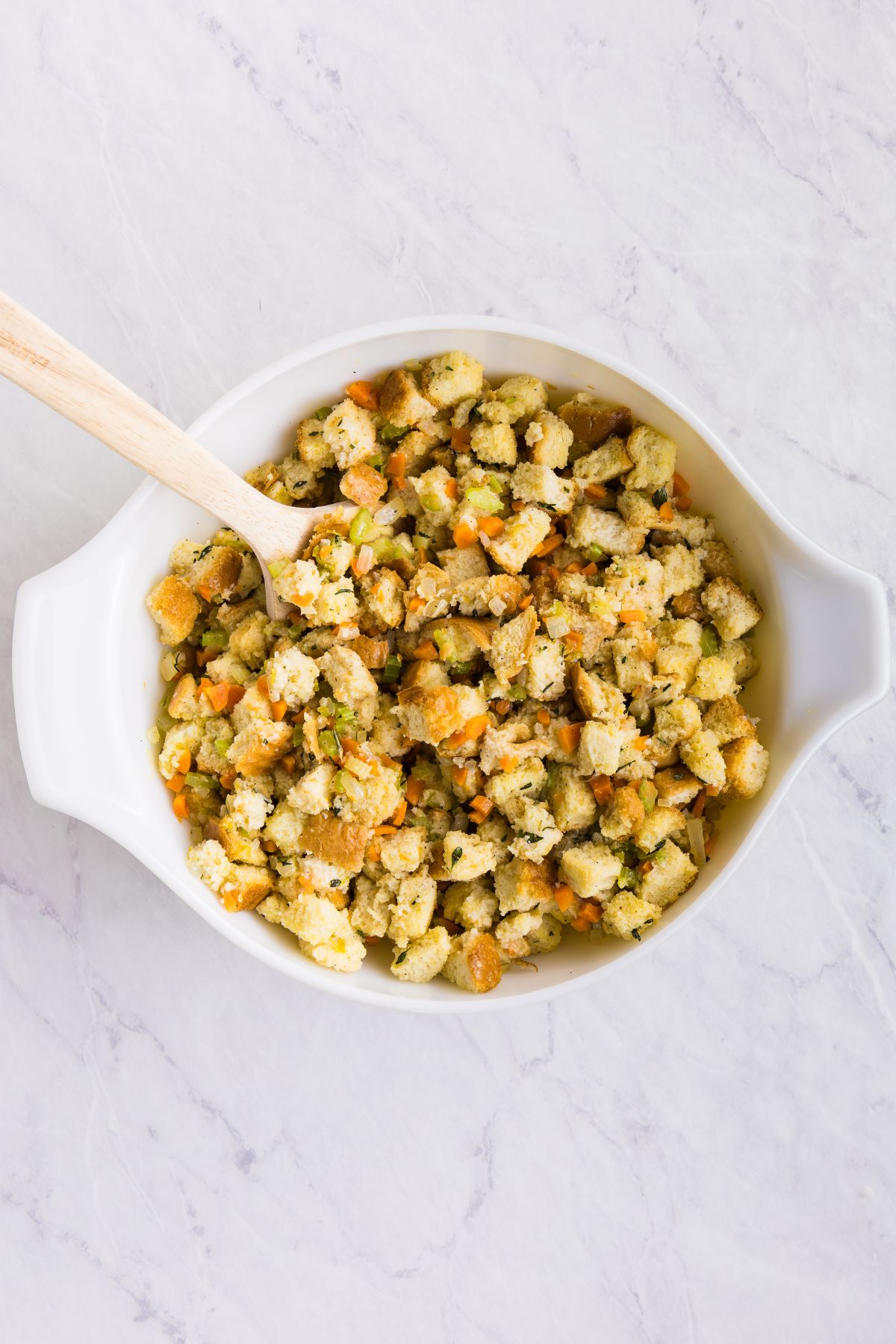 Cooked veggies, mixed with breadcrumbs and chicken stock, mixed with eggs, in a white bowl.