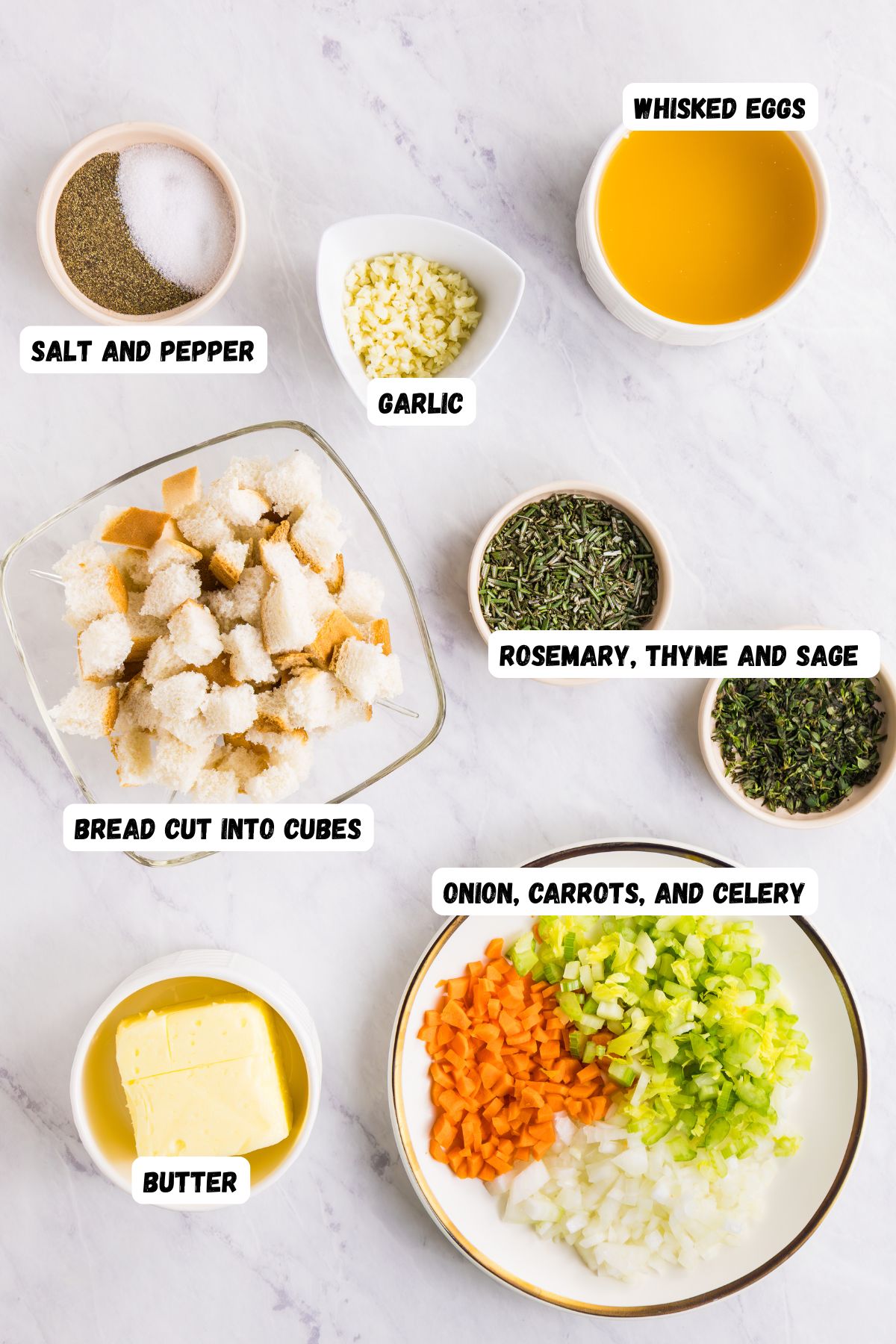 Ingredients needed to make homemade stuffing measured into small bowls on a marble table, and labeled.