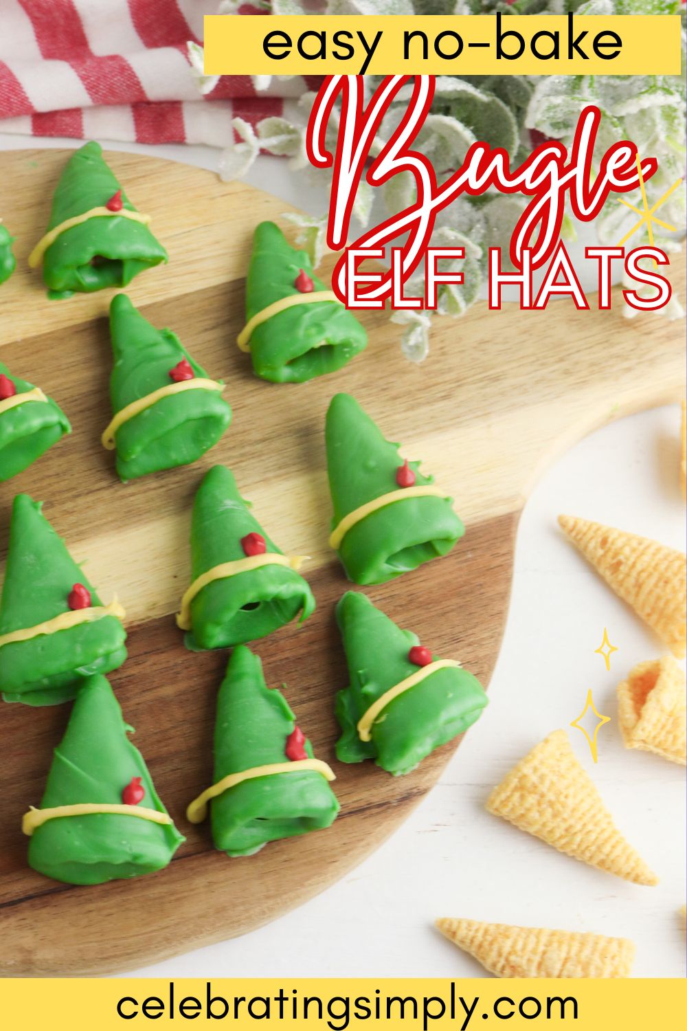 Chocolate coated green bugle chips, decorated to look like elf hats with yellow band and red feather, on a round wooden cutting board.