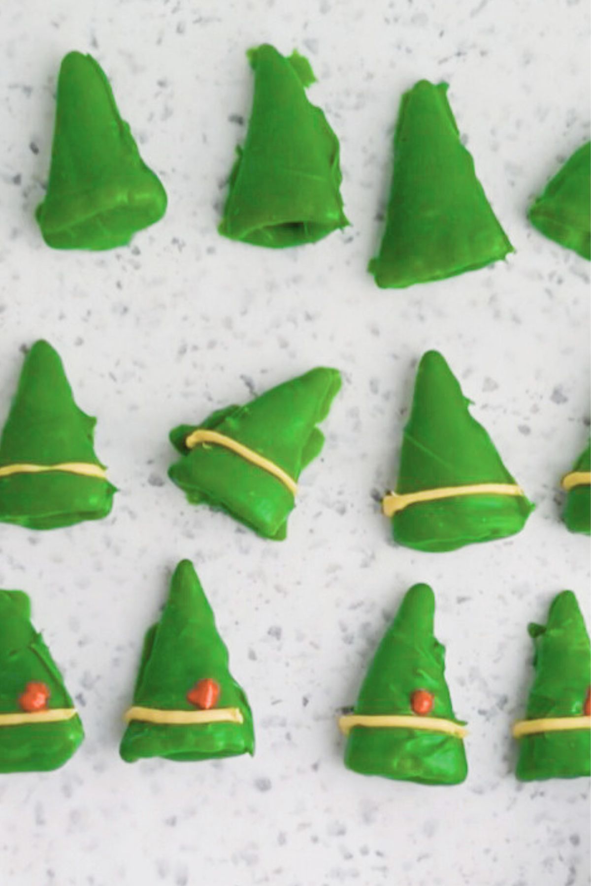 Green coated bugles, dried on parchment paper, then lined with a stripe of yellow and small dot of red melts to look like an elf hat. 