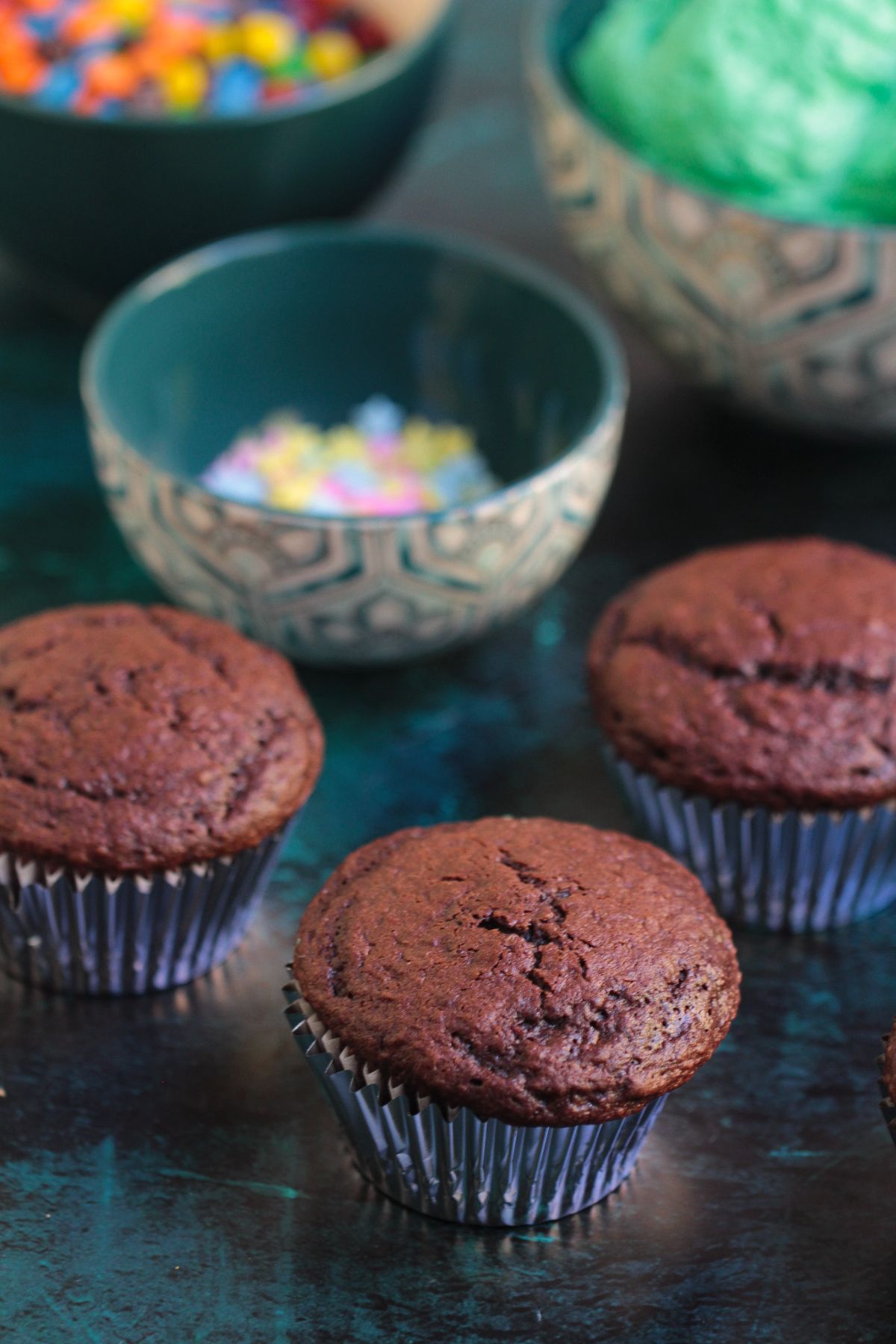 Chocolate cupcakes cooling on a table before frosting.
