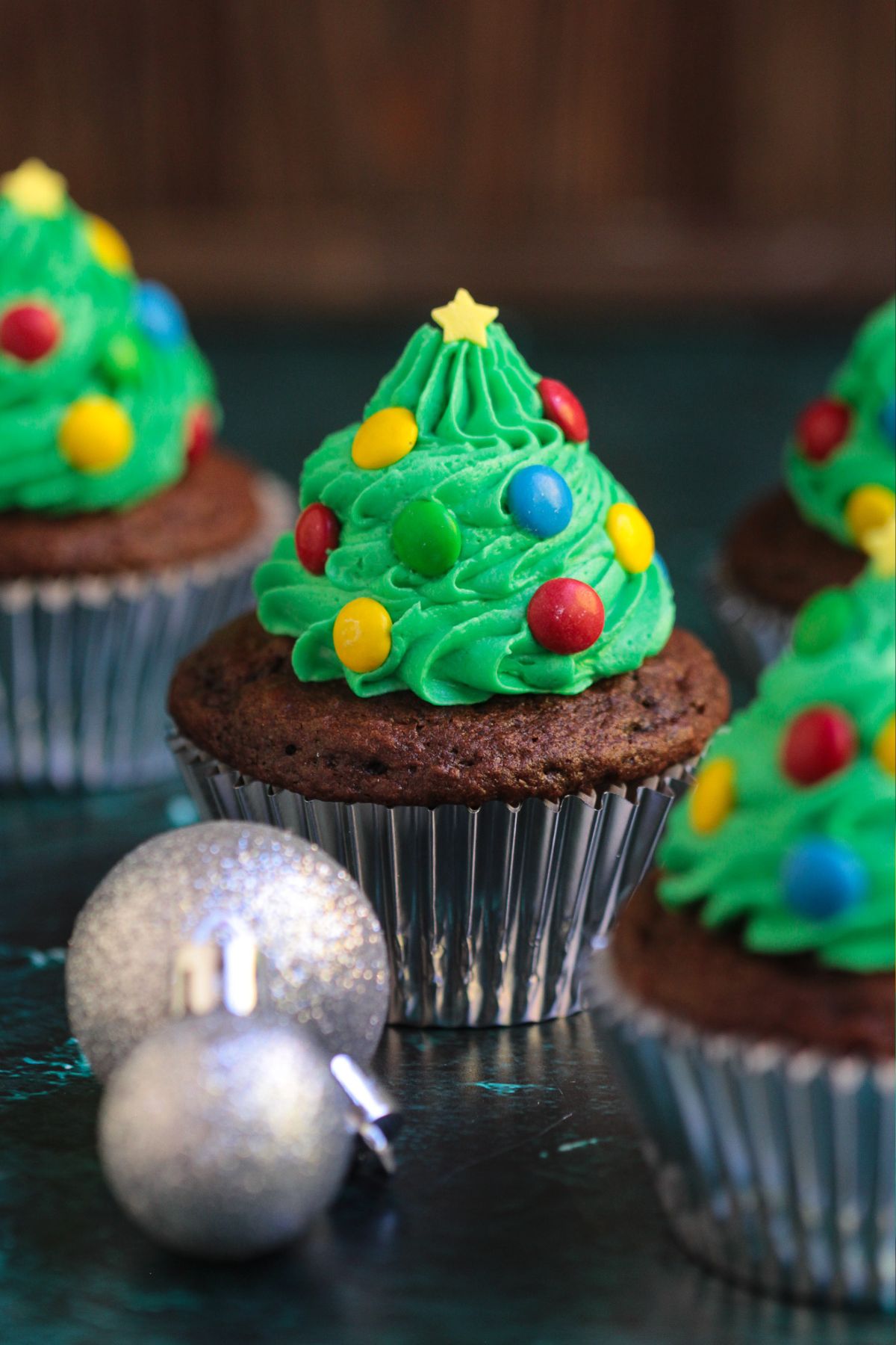 Chocolate cupcakes, frosting with green buttercream swirls in the shape of trees, decorated with mini candies for lights and star sprinkle for topper.